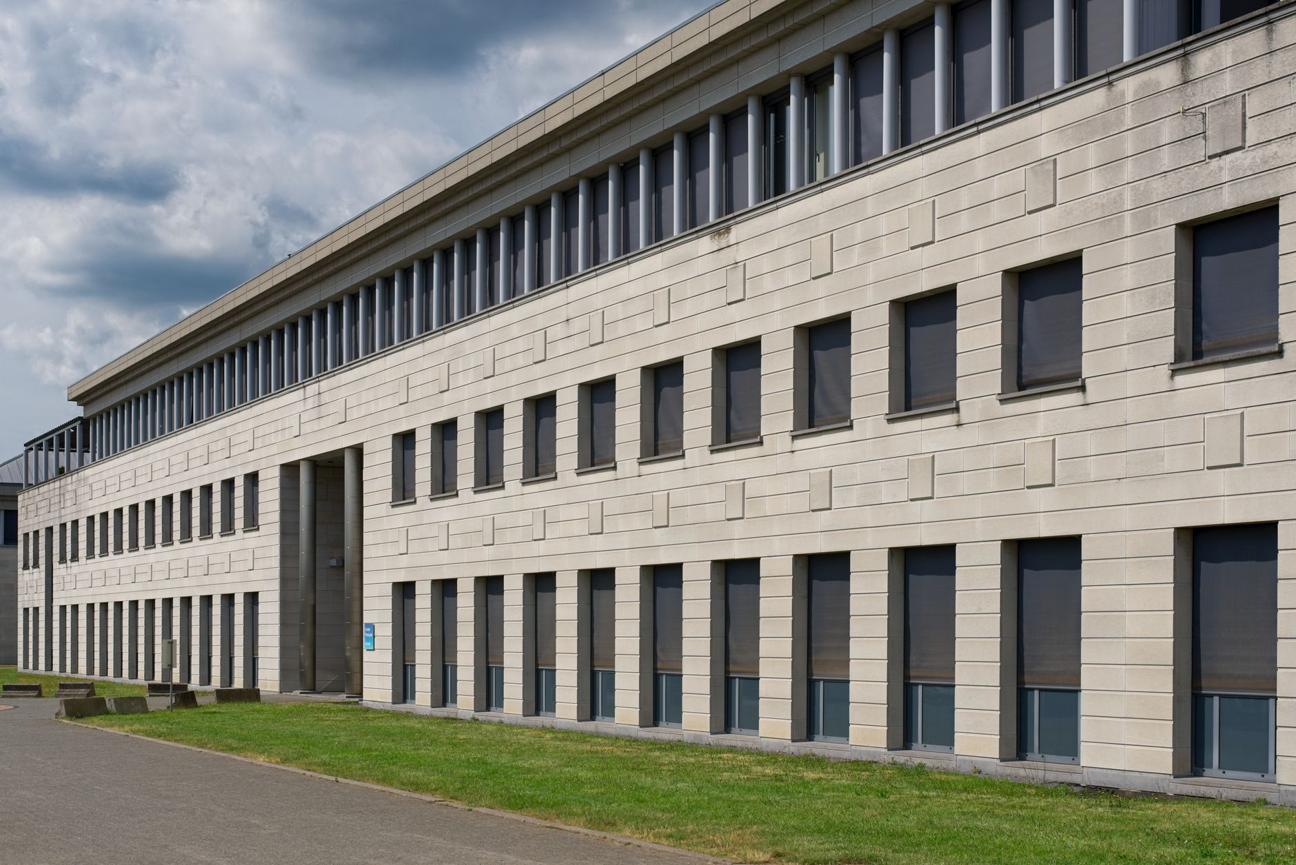 exterior of a large data center building at dusk with cooling infrastructure visible along the facade and a partly cloudy sky above