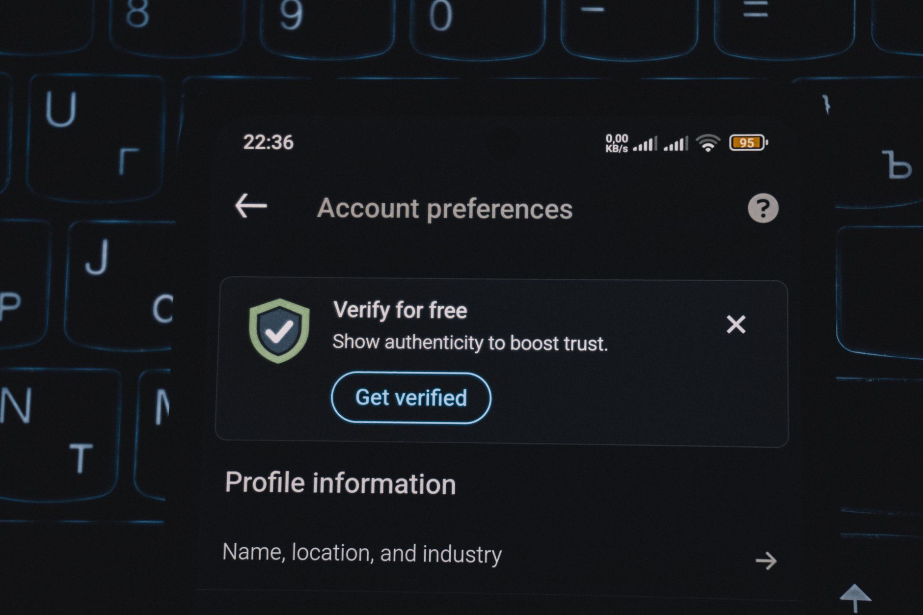 a smartphone screen displaying age verification prompts on a social media app, resting on a school desk with a blurred classroom background