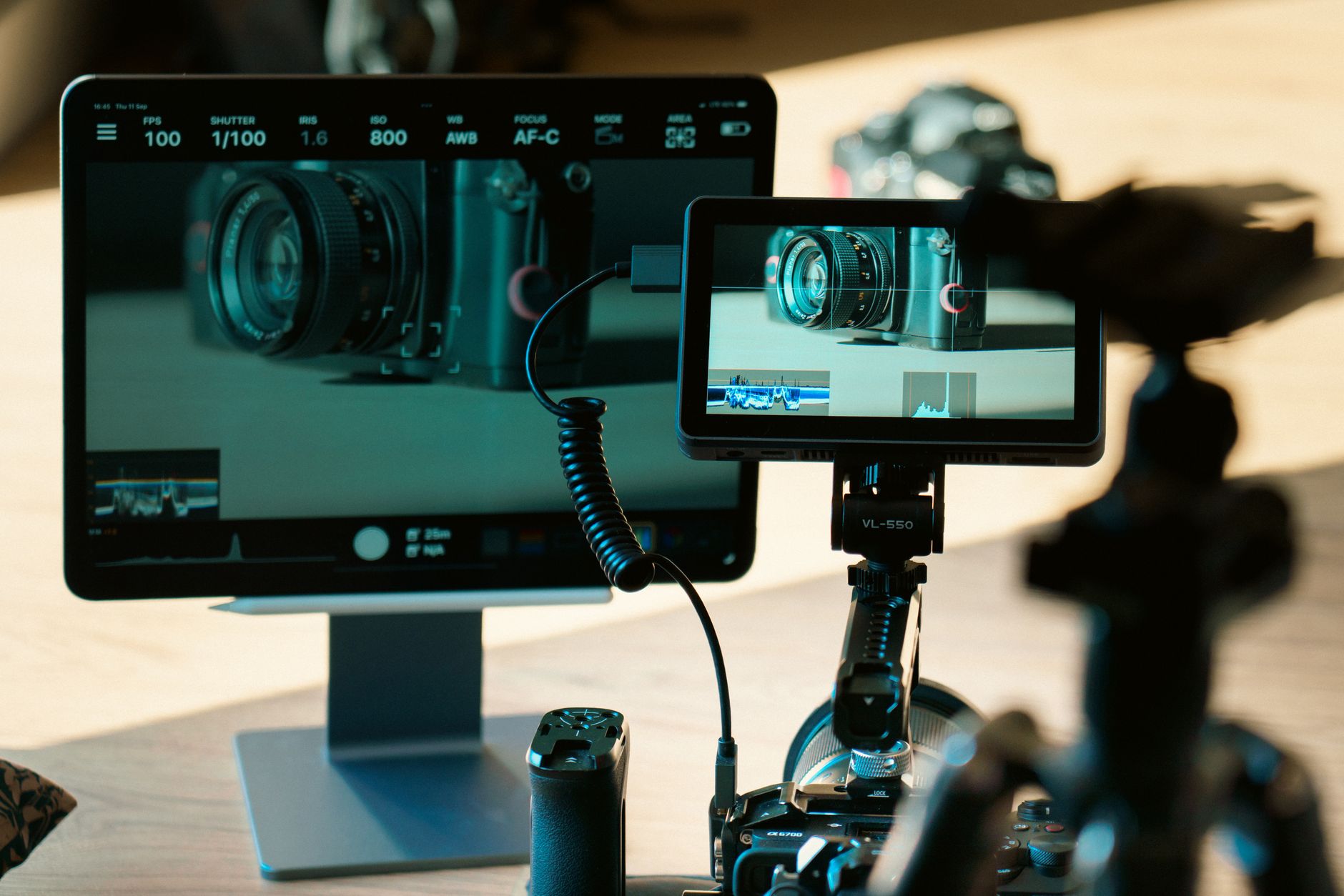 A close-up of a handheld dermoscopy imaging device resting on a clinical workstation next to a monitor displaying a high-resolution skin lesion analysis interface
