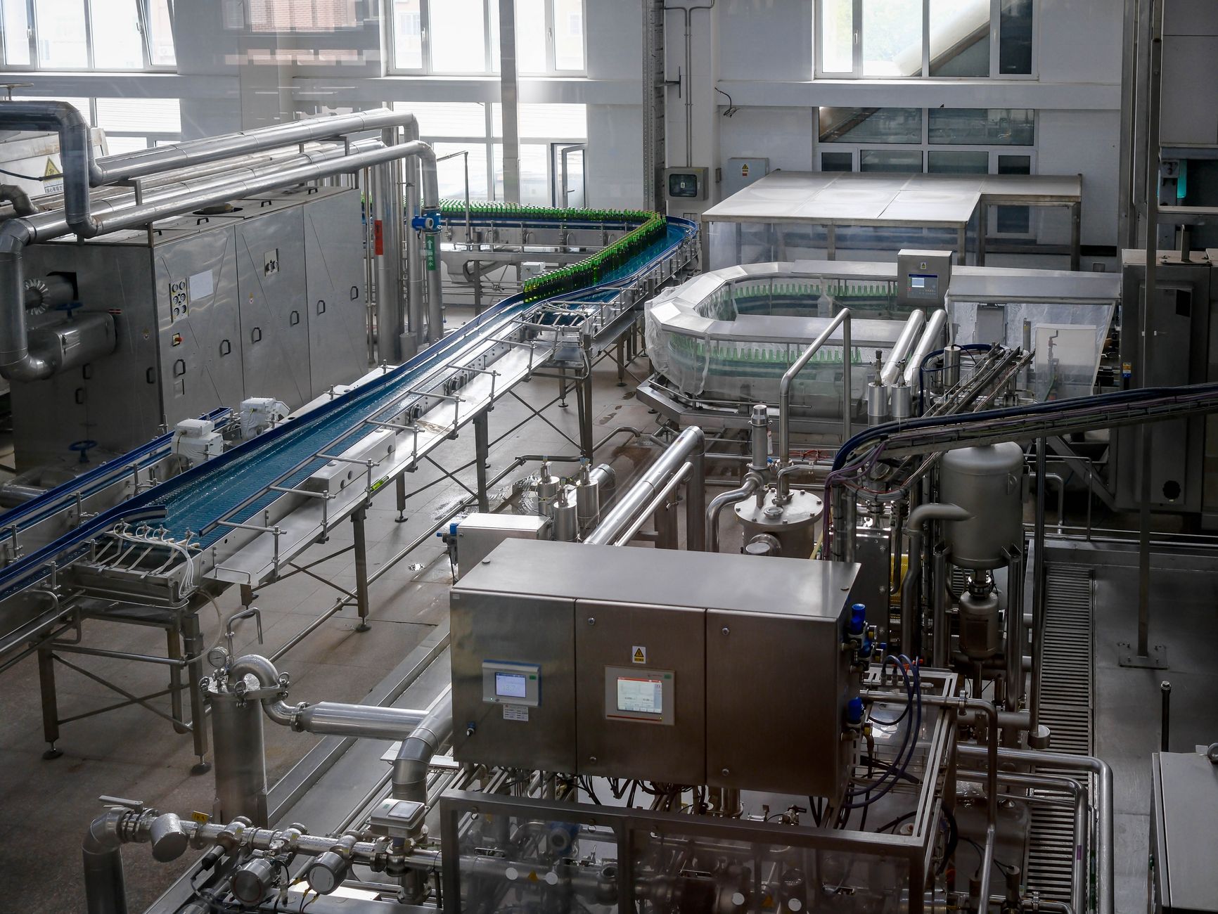 wide-angle interior of a large industrial warehouse with automated conveyor systems and empty floor space, bright overhead lighting