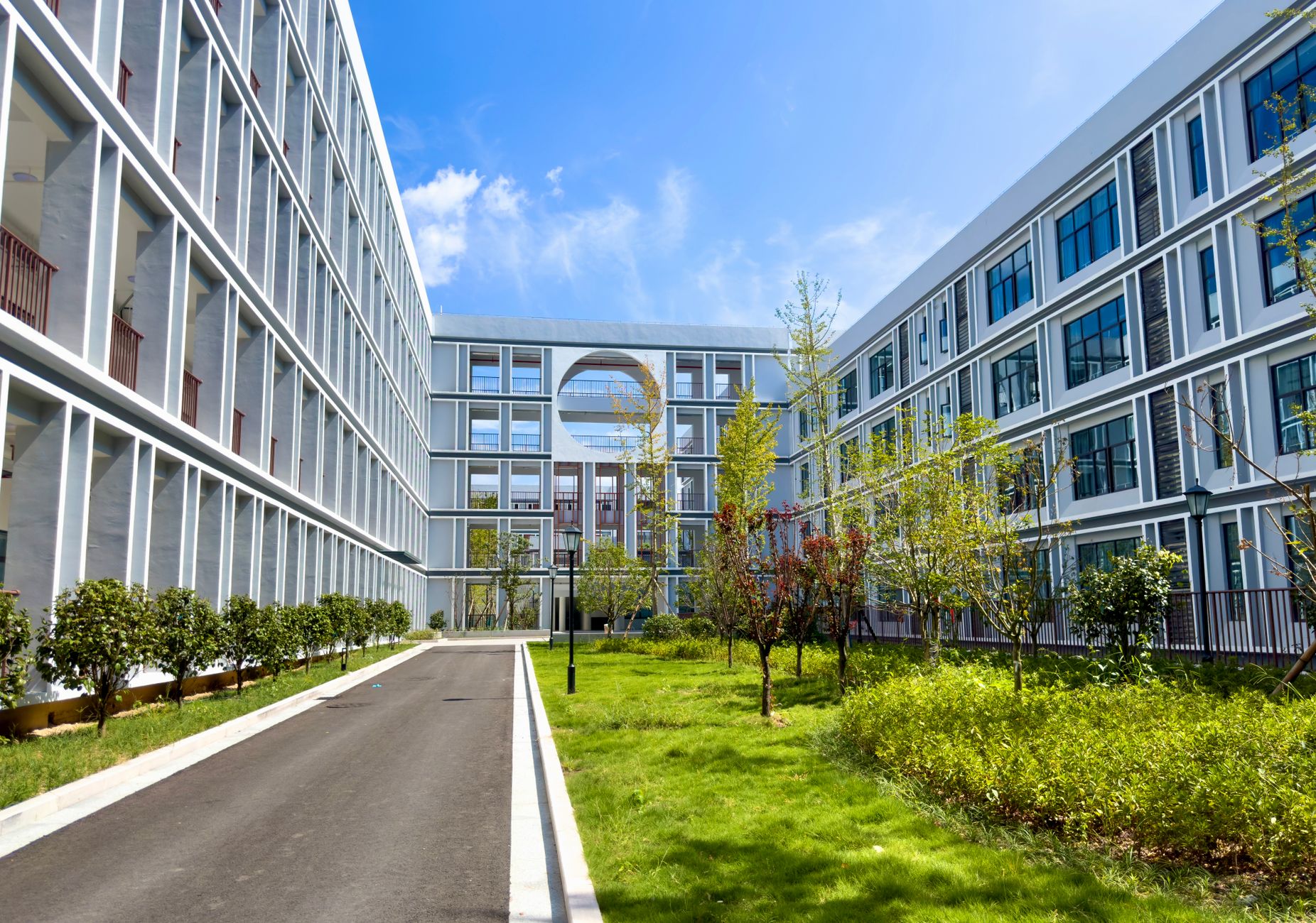 a glass-fronted corporate technology campus building exterior at dusk with interior office lights visible and a manicured courtyard in the foreground