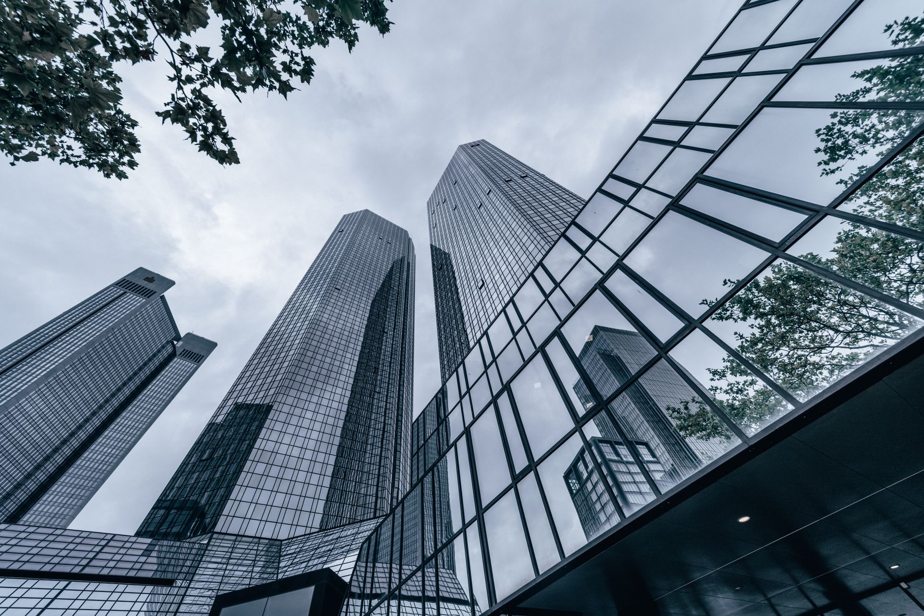 a wide-angle view of a modern Tel Aviv office tower at dusk, with lit floors visible through glass facades and a city skyline in the background