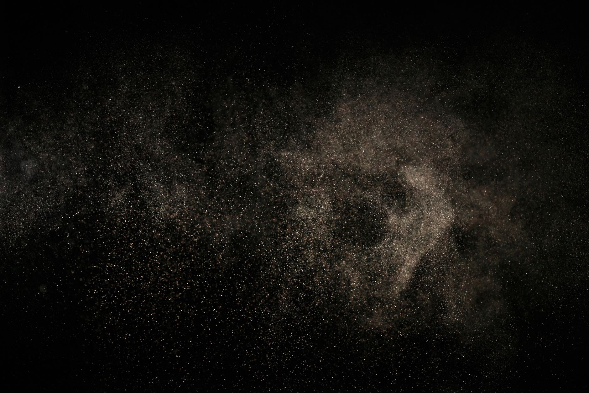 close-up of fine orange-tinted dust particles settled on a flat outdoor surface under bright sunlight, with heat shimmer visible in the background