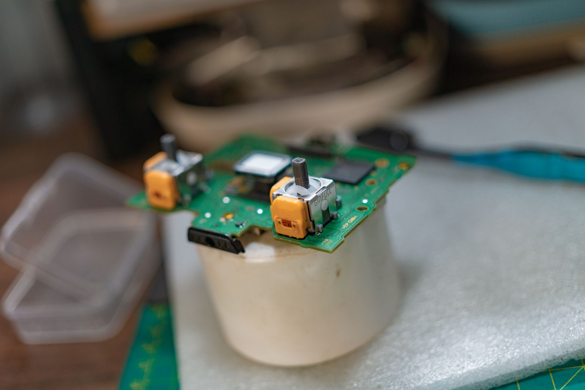 a close-up of a small AI accelerator chip module mounted on a green PCB, surrounded by passive components, sitting on an engineering workbench