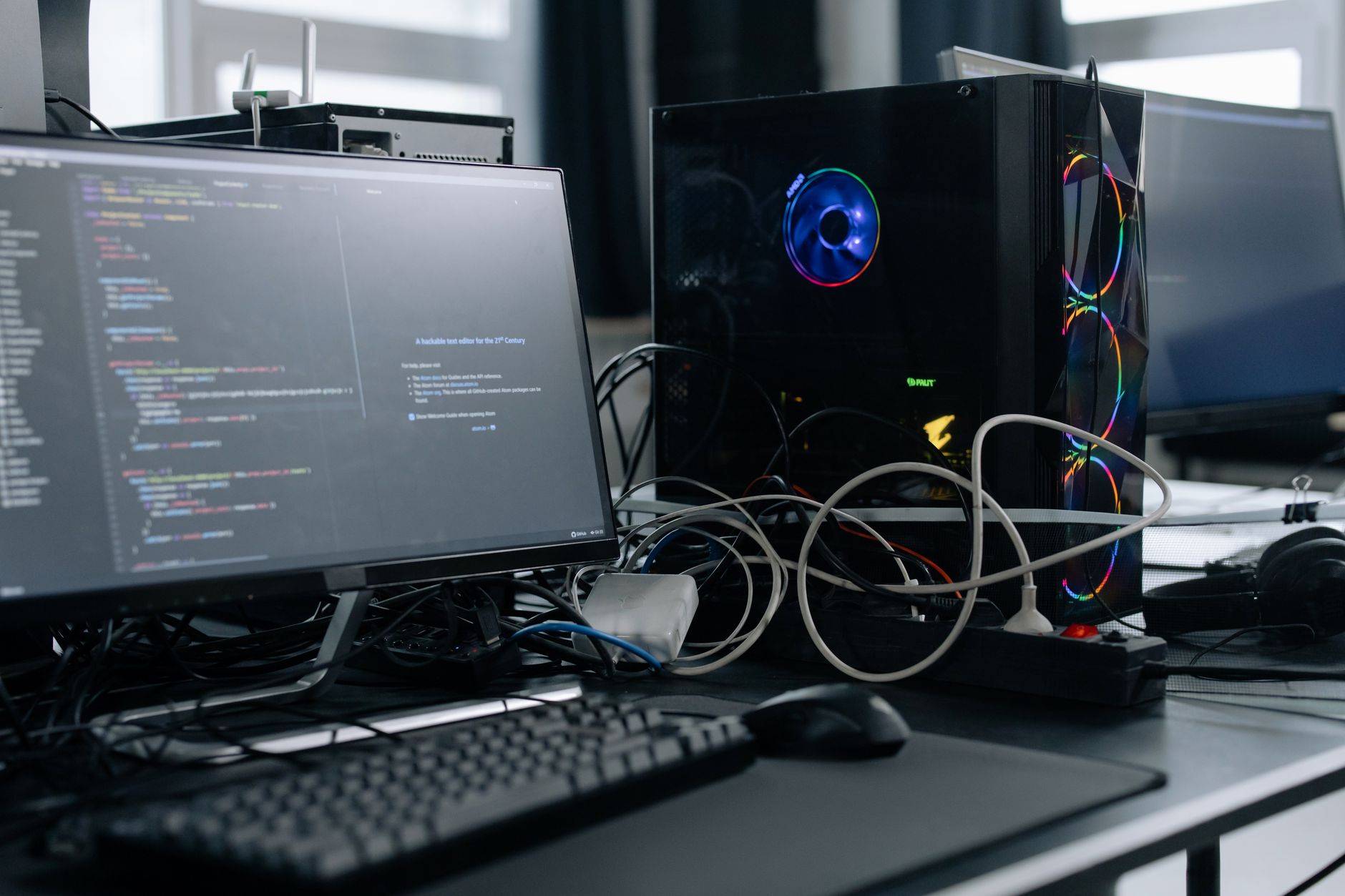 a developer workstation displaying lines of code and model training metrics on dual monitors in a dimly lit office environment