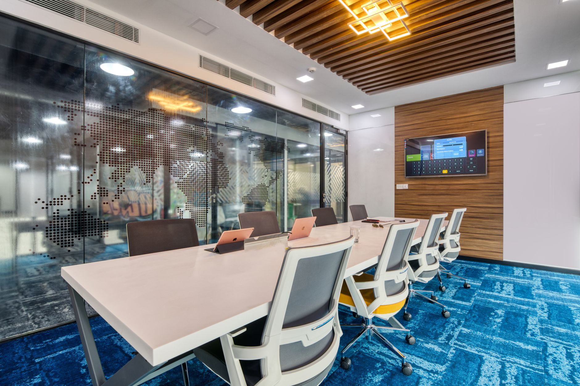 a glass-walled private equity office floor with rows of empty analyst workstations and a large wall-mounted display showing a company valuation timeline graph