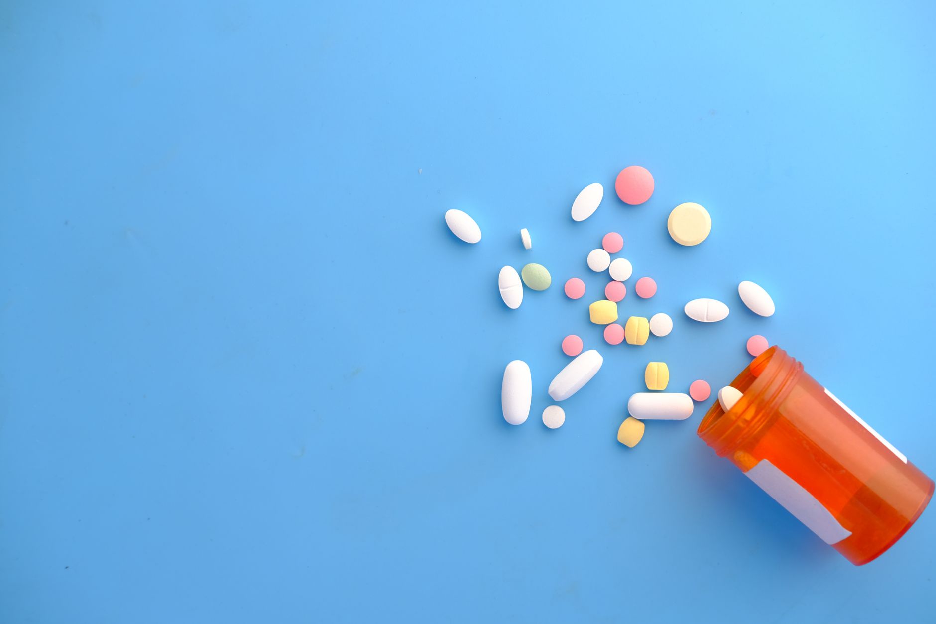 Rows of amber prescription antibiotic bottles lined up on a clinical pharmacy counter under bright overhead lighting