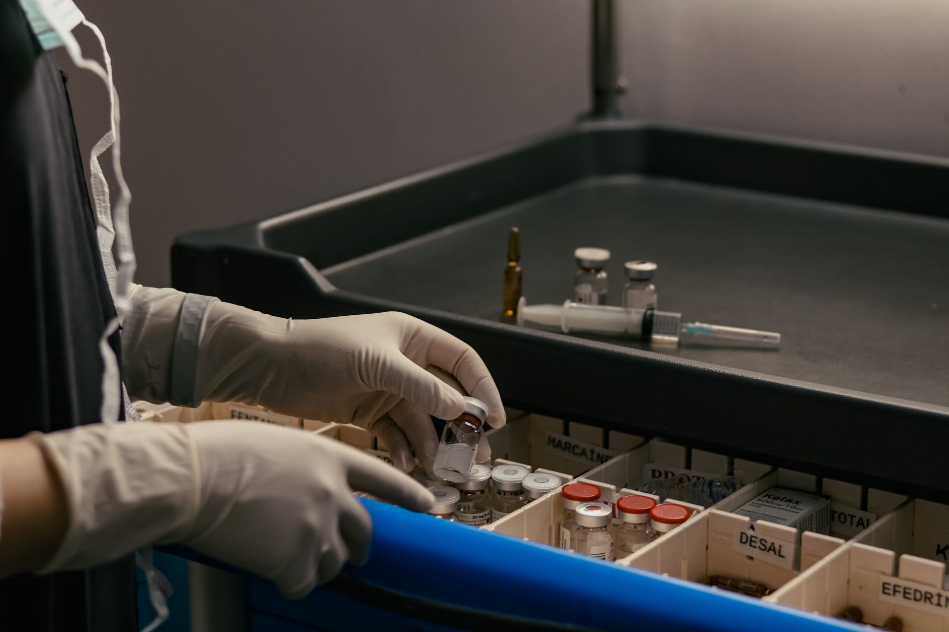rows of pharmaceutical compound vials arranged in a clinical laboratory storage rack under bright white overhead lighting