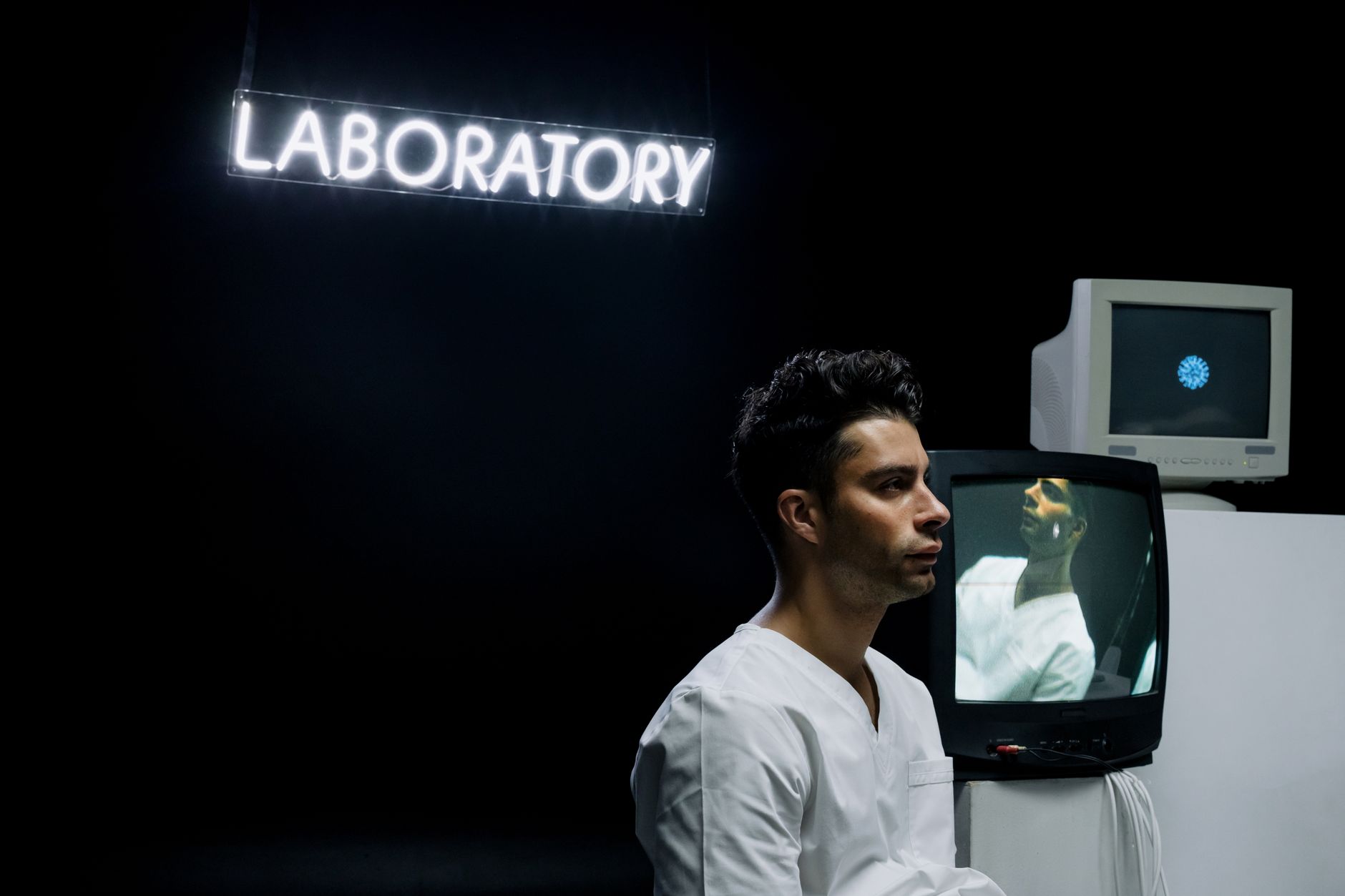 a wide shot of a sleek AI research lab interior at night, rows of illuminated workstations and wall-mounted monitors displaying neural network visualizations, no people in foreground