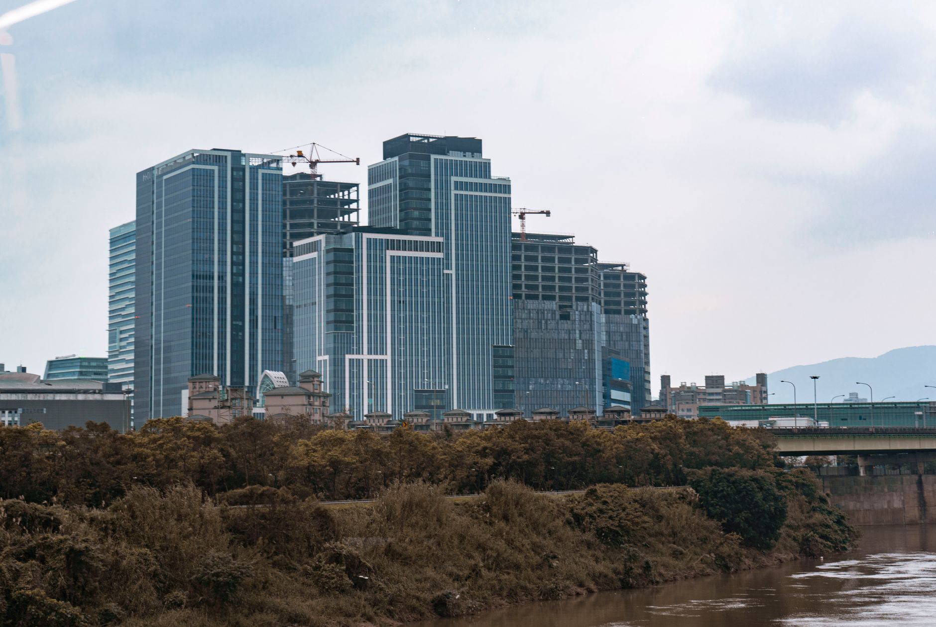 aerial view of two busy commercial districts separated by open water, office towers visible on both shorelines under overcast sky