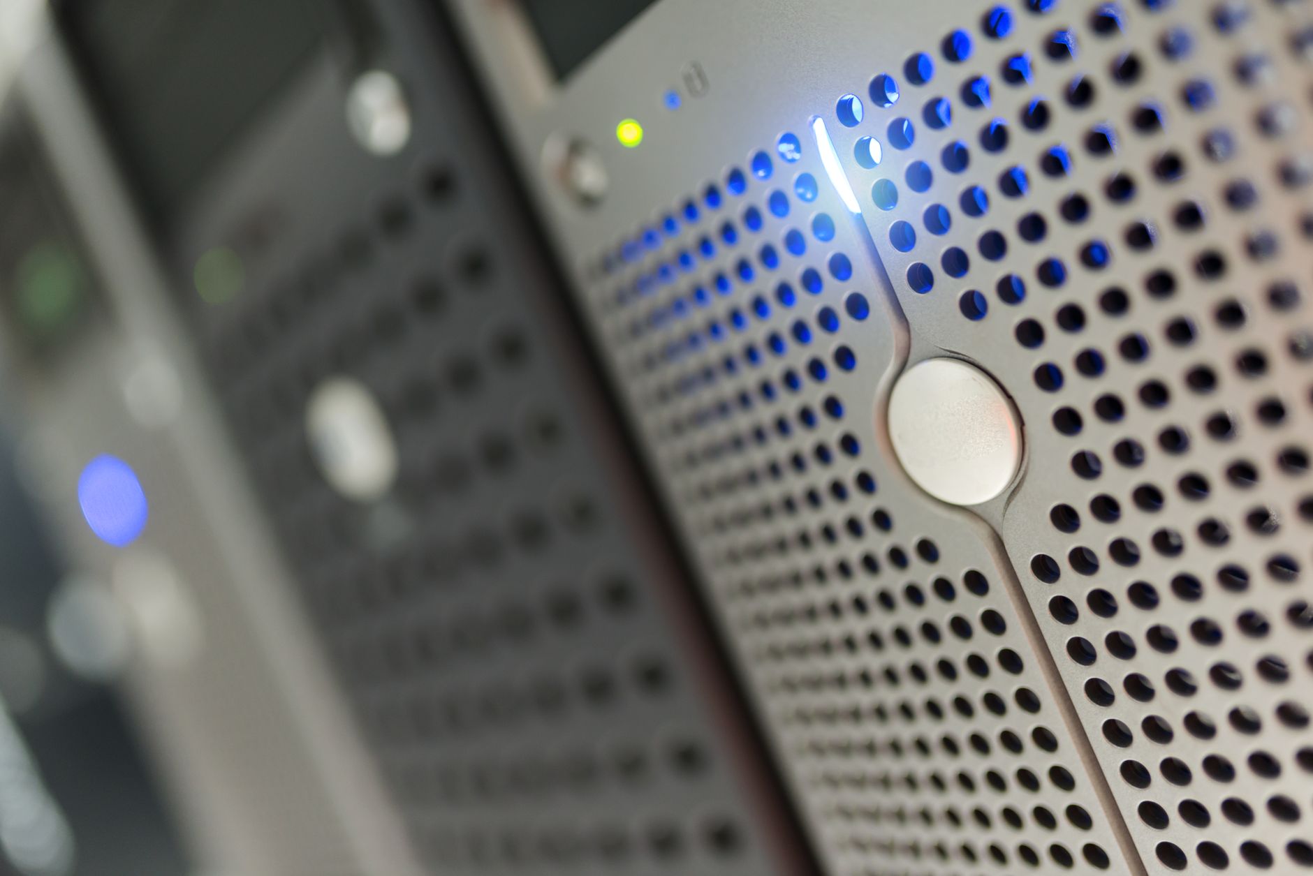 rows of enterprise server racks inside a modern data center, illuminated by blue overhead lighting with cable trays running along the ceiling
