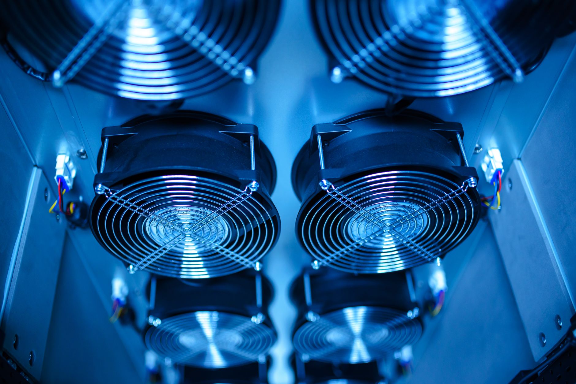 rows of GPU server racks inside a large data center facility, cooling units visible along the walls, indicator lights blinking across the hardware