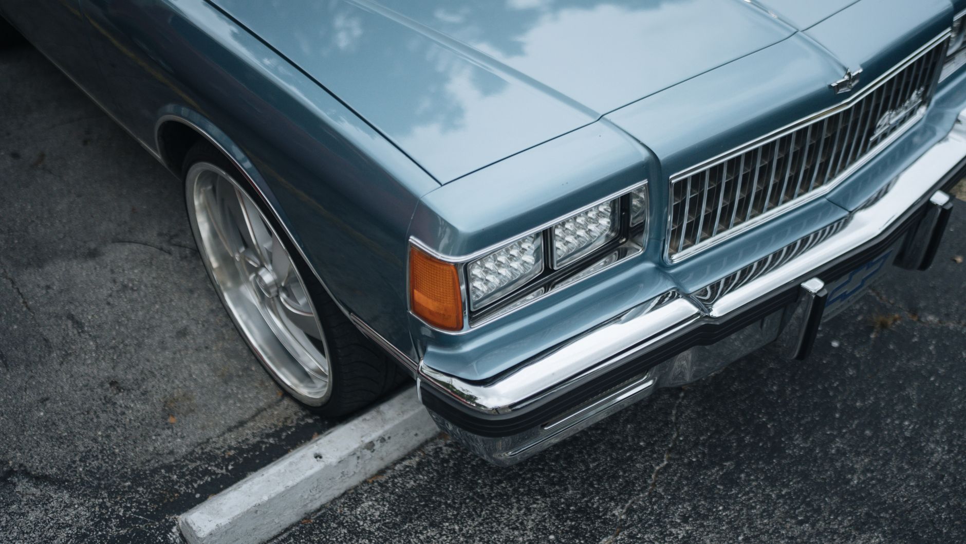 a close-up of a compact automotive radar module mounted behind a vehicle's front bumper, set against a blurred urban street background