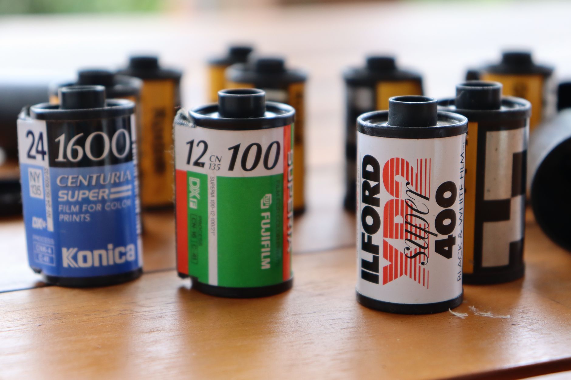 A row of instant photo prints in different sizes laid flat on a light surface, showing the distinct color tones and border styles of different camera formats