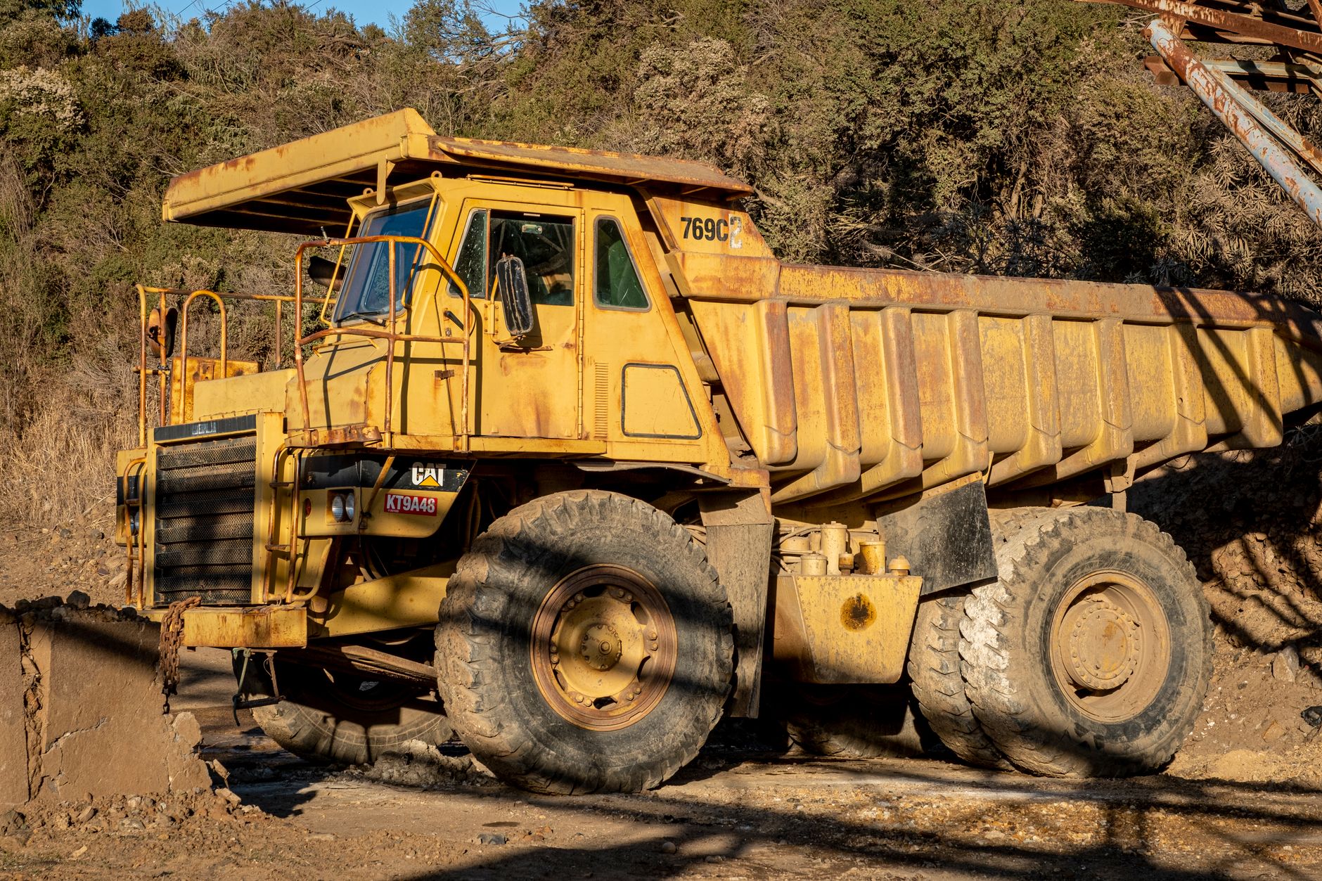 a large autonomous haul truck navigating a dusty open-pit copper mine at dusk, with sensor arrays visible on its roof cab