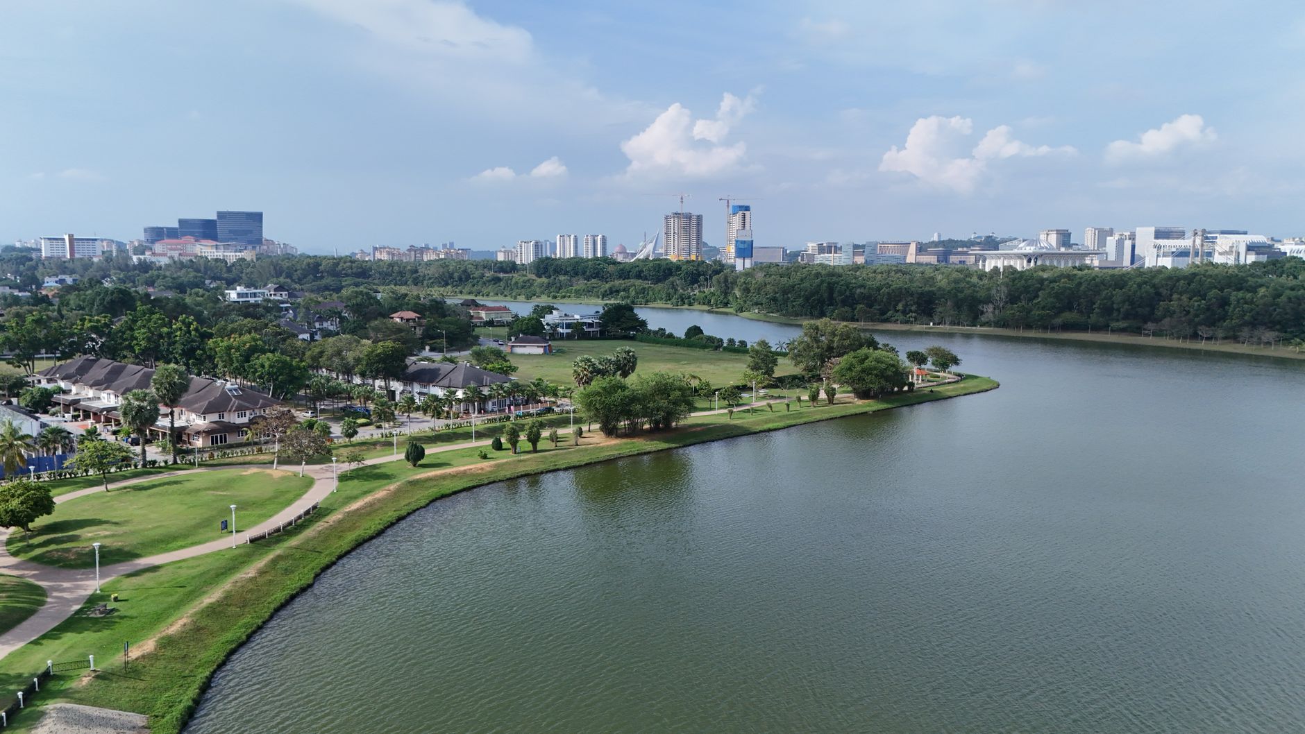 wide aerial view of a large modern convention center surrounded by tropical landscaping, with a river visible in the background at dusk