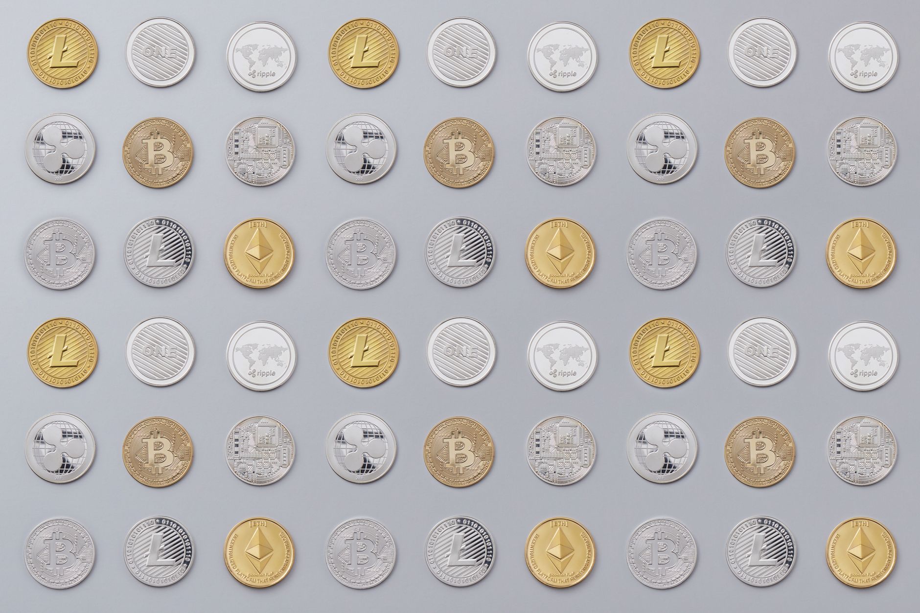 Close-up of several silver and gold collectible coins arranged on a flat surface under bright studio lighting, showing surface details and edge lettering