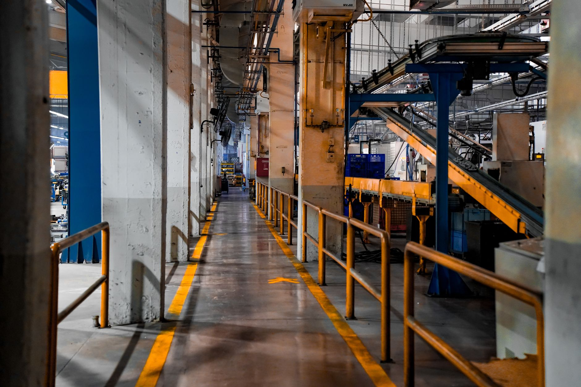 rows of cylindrical battery cells in various stages of assembly inside a clean manufacturing facility, with industrial equipment visible along the walls