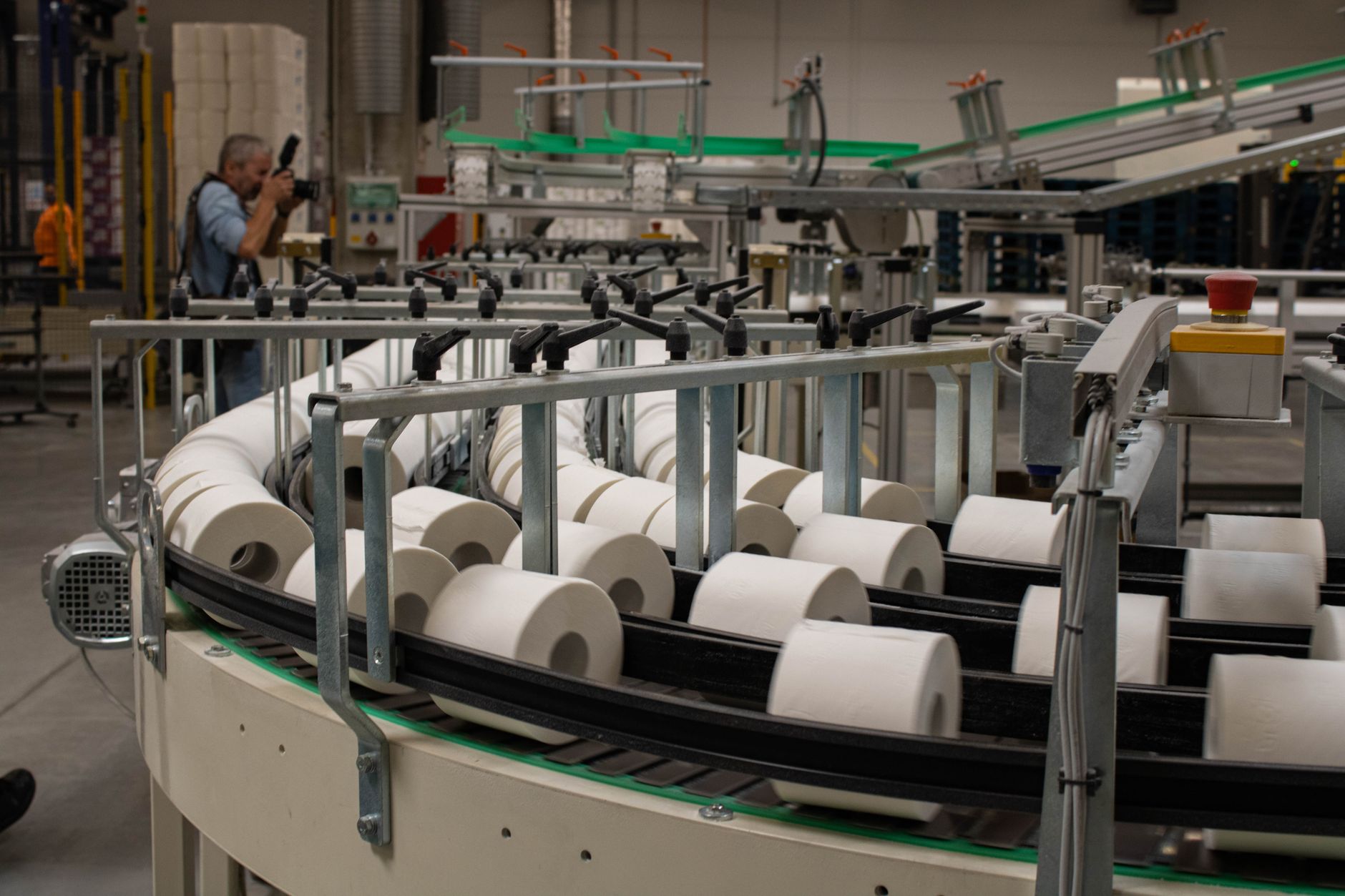 rows of industrial textile finishing machinery inside a large production facility, with fabric rolls feeding through rollers