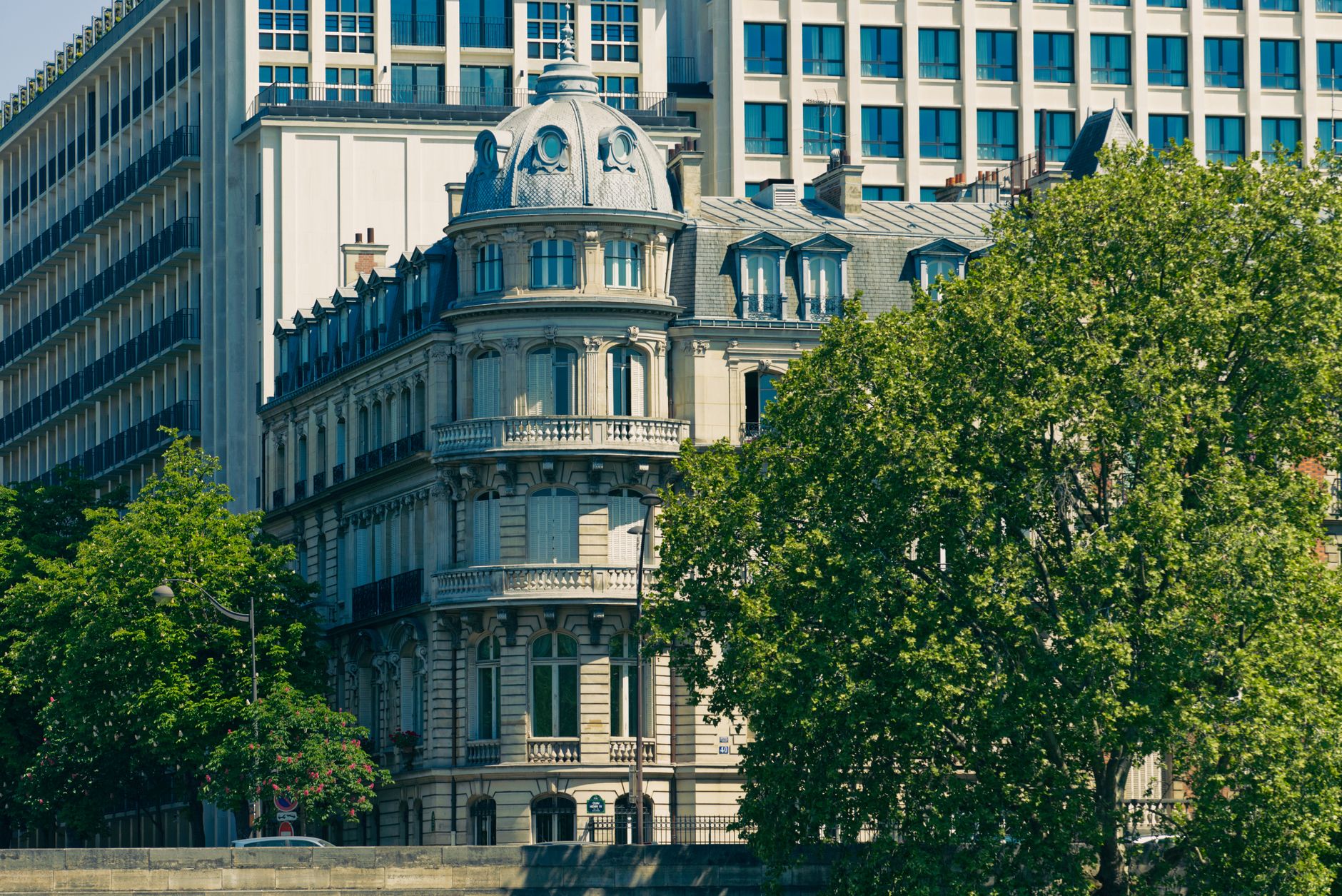exterior of a historic European consulate building on a tree-lined urban street, afternoon light casting long shadows across stone steps