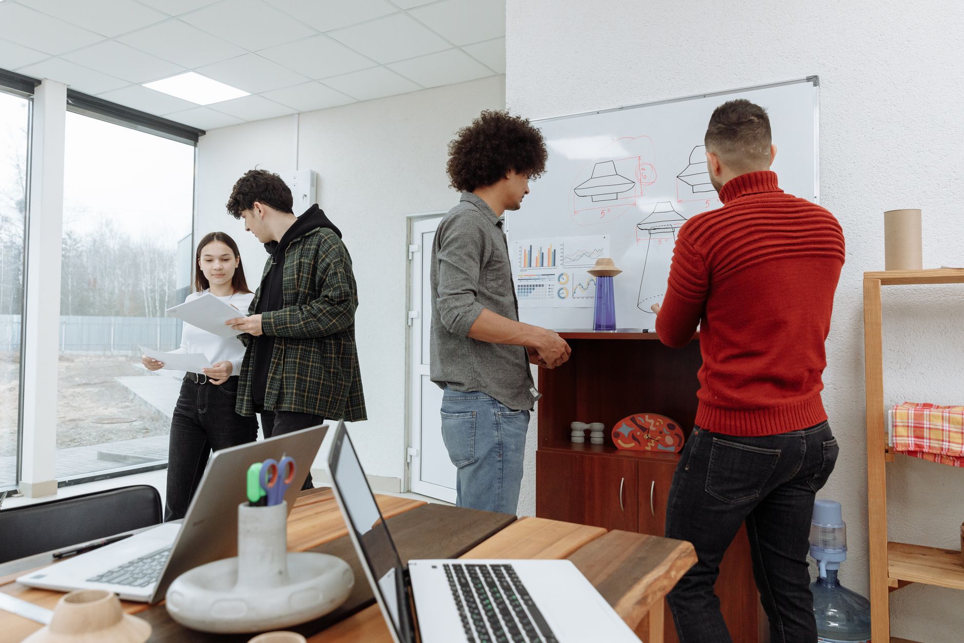 rows of startup pitch decks and product prototypes displayed on tables inside a bright innovation hub, natural light coming through floor-to-ceiling windows
