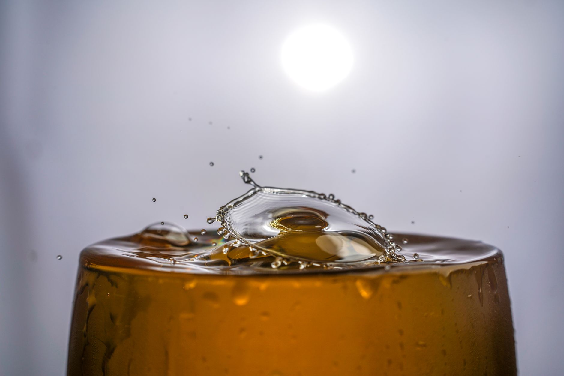 Close-up of a glass filled with clear water on a white kitchen countertop, afternoon sunlight refracting through the liquid