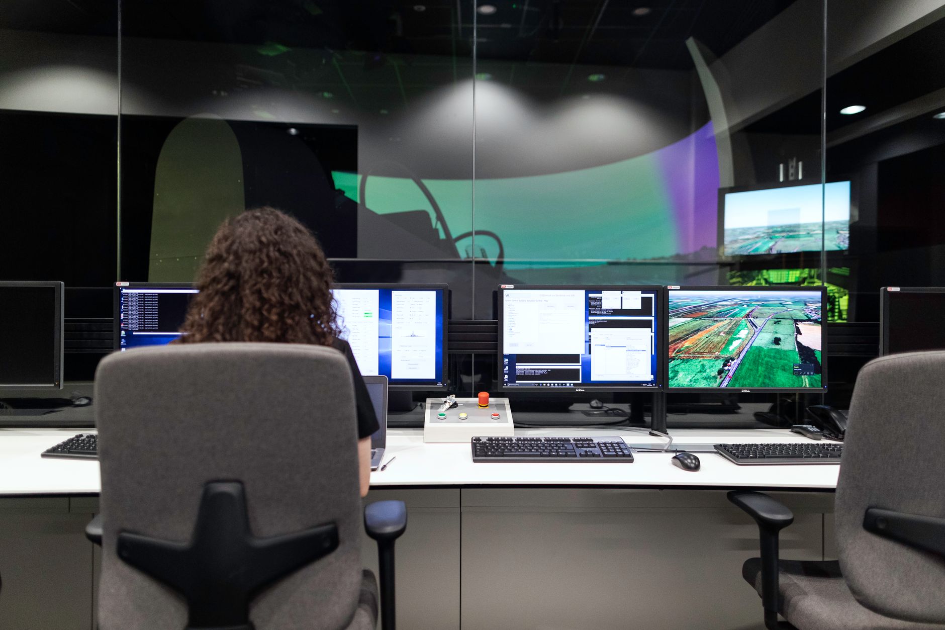 MRI control room with a wall of monitors displaying real-time thermal brain imaging maps in false color, consoles and keyboards in the foreground, no people as focal point