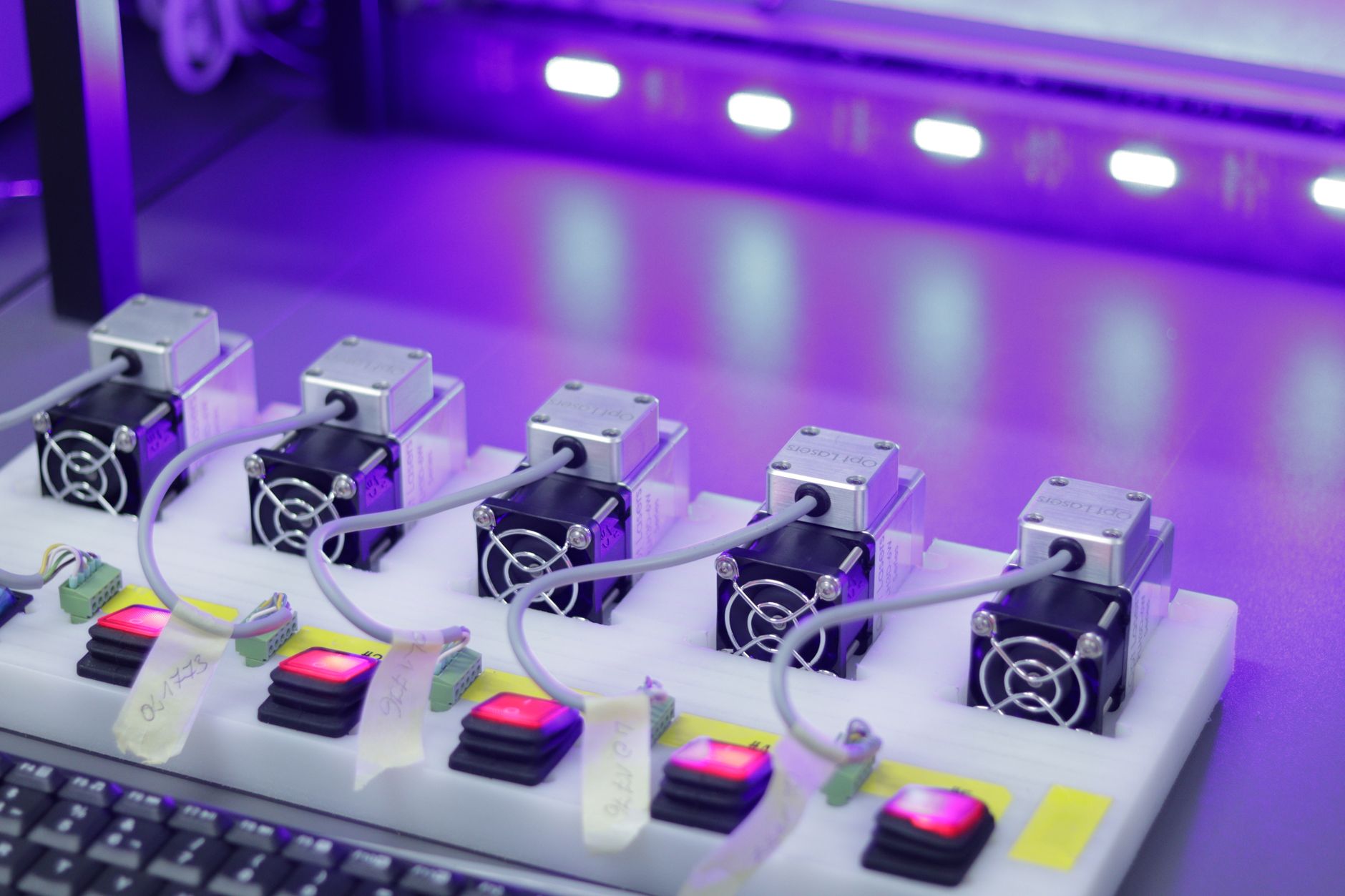 a small satellite assembly cleanroom with modular spacecraft components arranged on work benches under white LED lighting