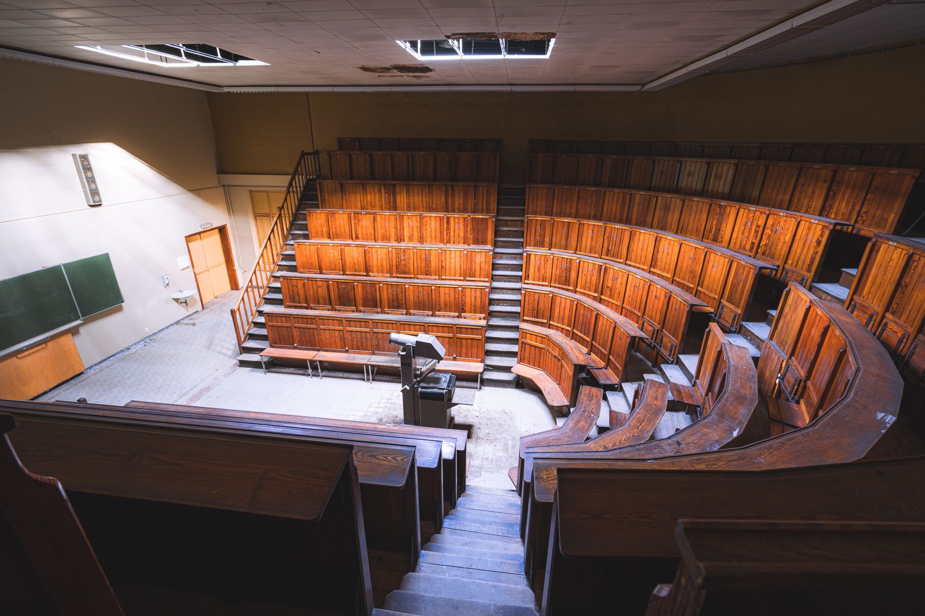 a university lecture hall auditorium with rows of empty seats facing a large projector screen displaying a technical engineering presentation slide