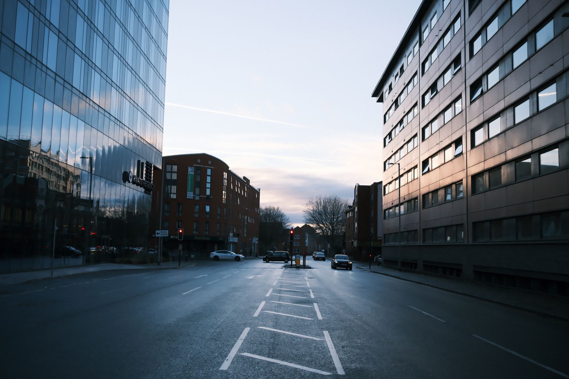 a wide-angle view of a technology campus at dusk in an urban Indian city, with softly lit office buildings visible through glass facades and street traffic in the foreground
