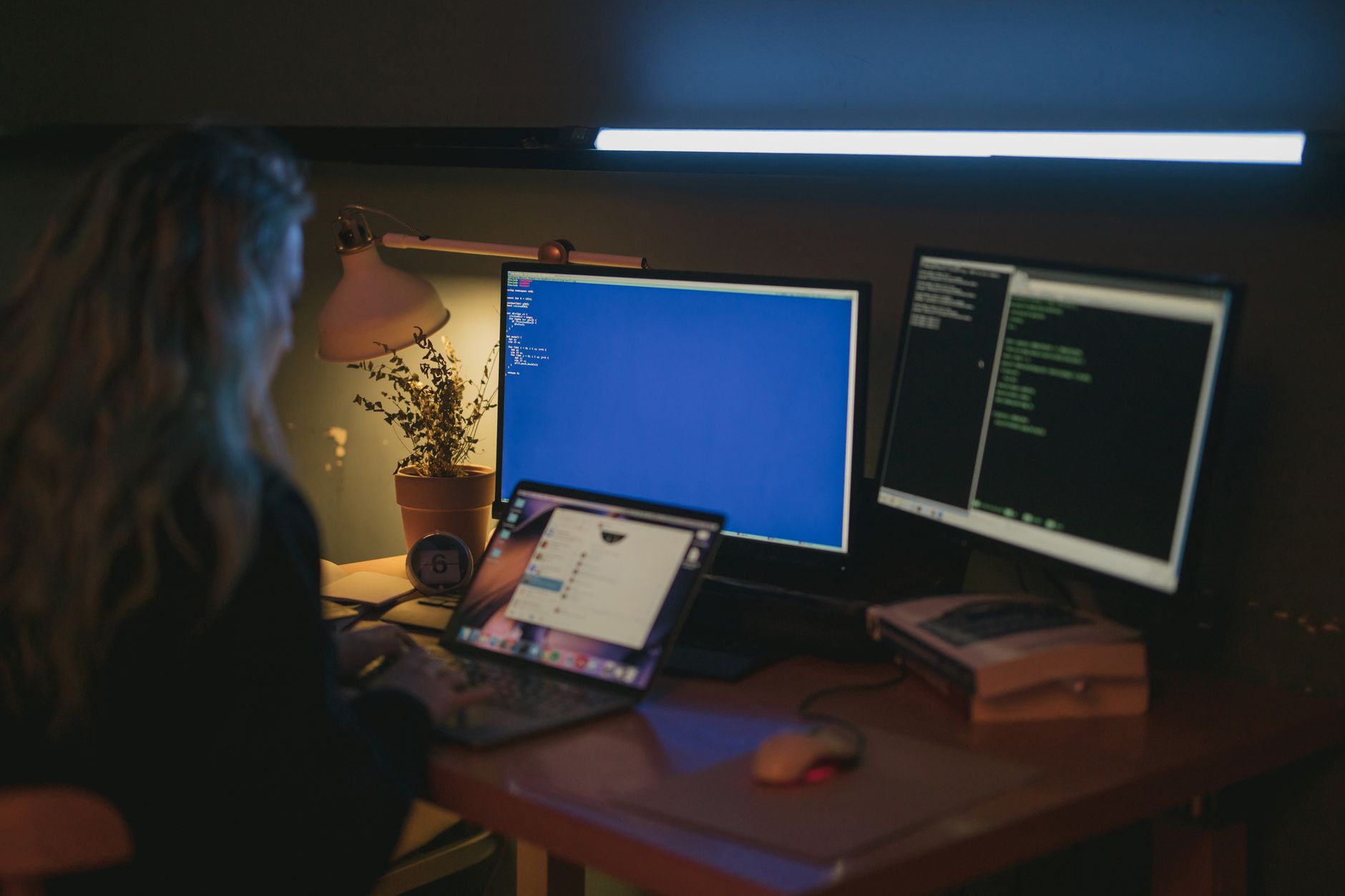 a modern open-plan startup office with multiple monitor setups showing software dashboards and code editors, no people as focal point