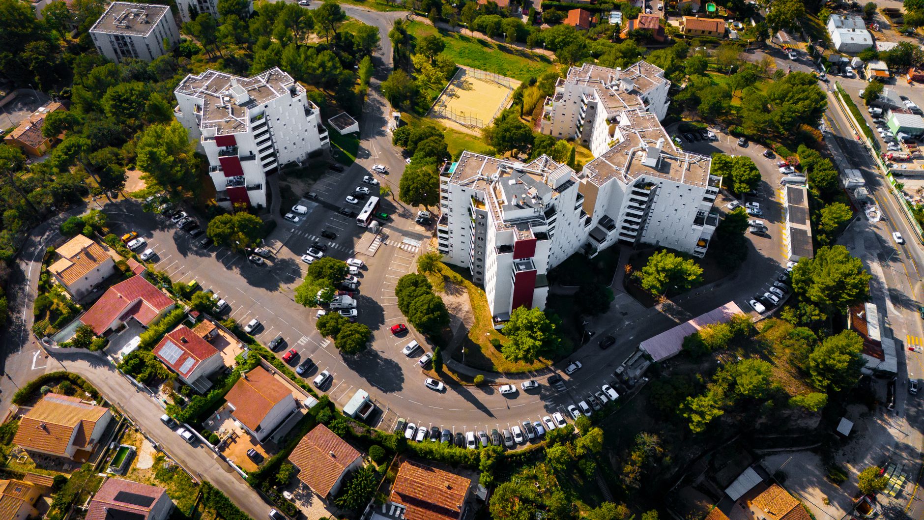 aerial view of a large modern corporate campus surrounded by Mediterranean-style urban development, with parking structures and glass office buildings visible from above