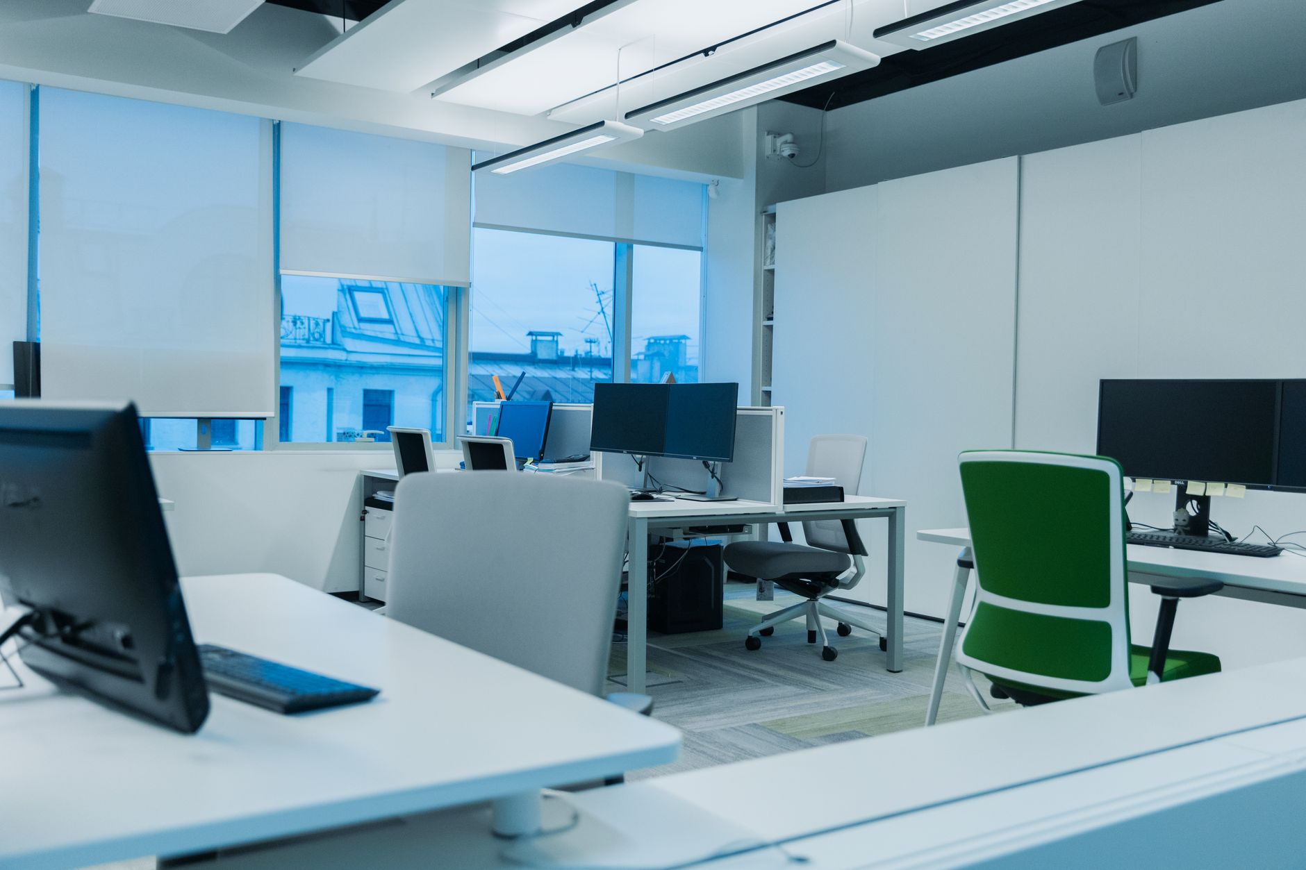 a wide-angle view of a government innovation center interior with large digital display screens showing data dashboards and a rows of workstations in a modern open-plan office