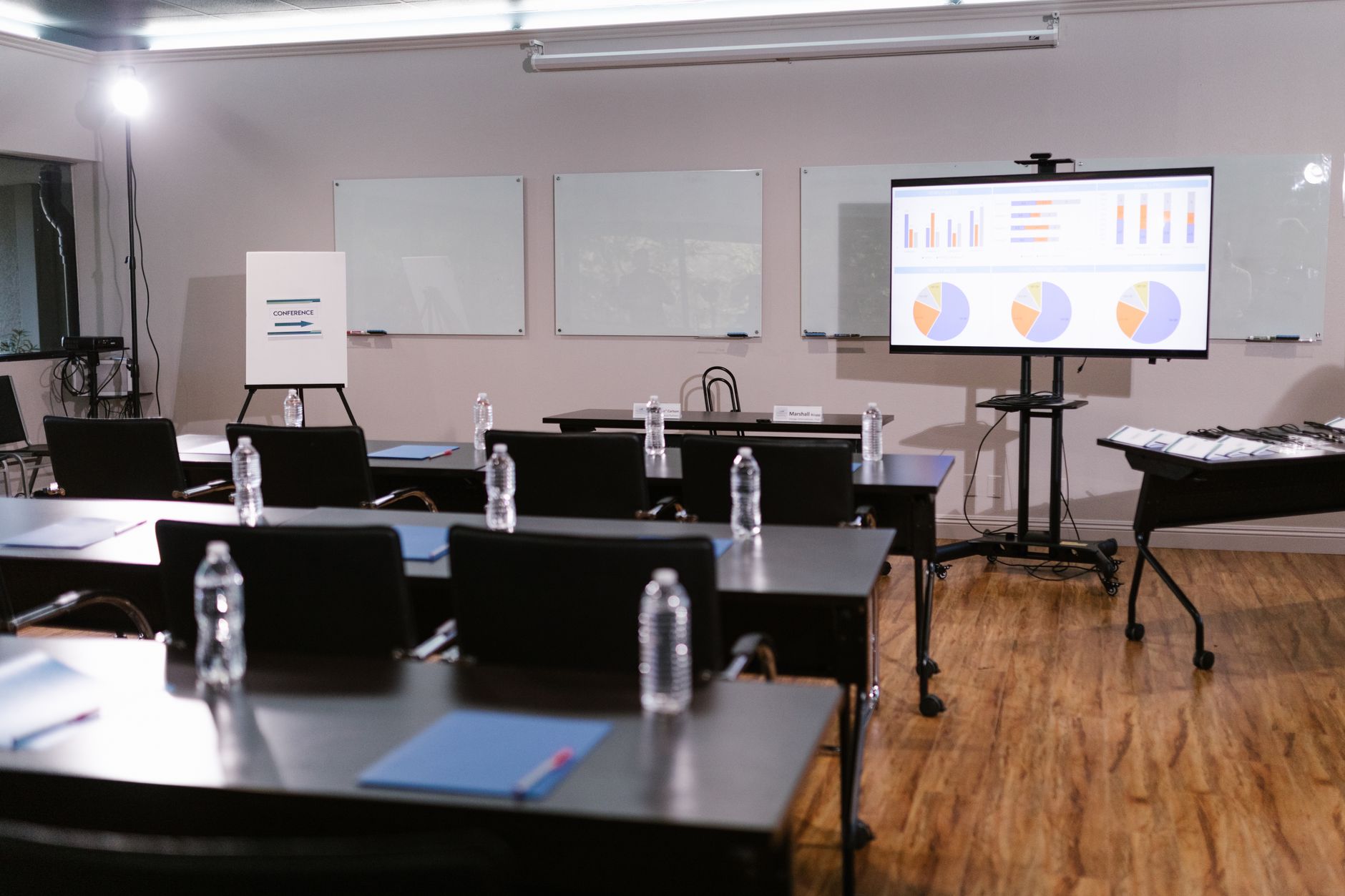 a wide shot of a corporate boardroom with a large display screen showing a shareholder vote tally, empty chairs arranged around a polished conference table