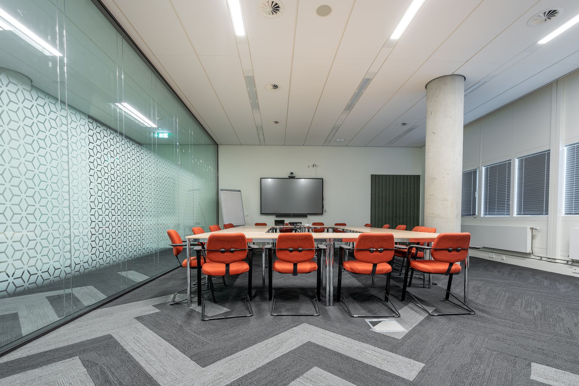 a modern corporate boardroom with a large digital voting display screen showing stockholder meeting details, empty chairs around a long conference table
