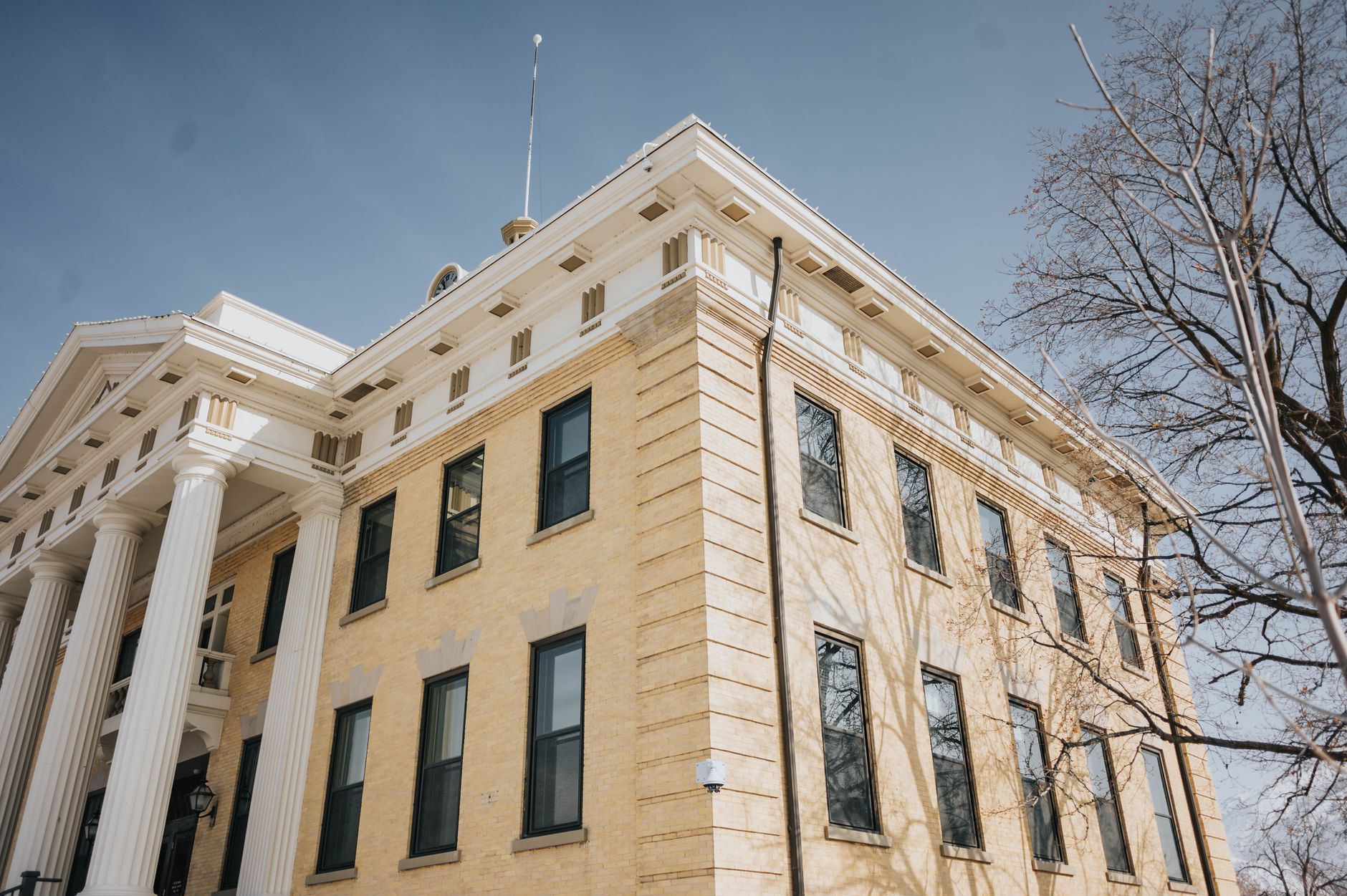 a wide-angle view of a state courthouse exterior with stone steps and tall columns, afternoon sunlight casting long shadows