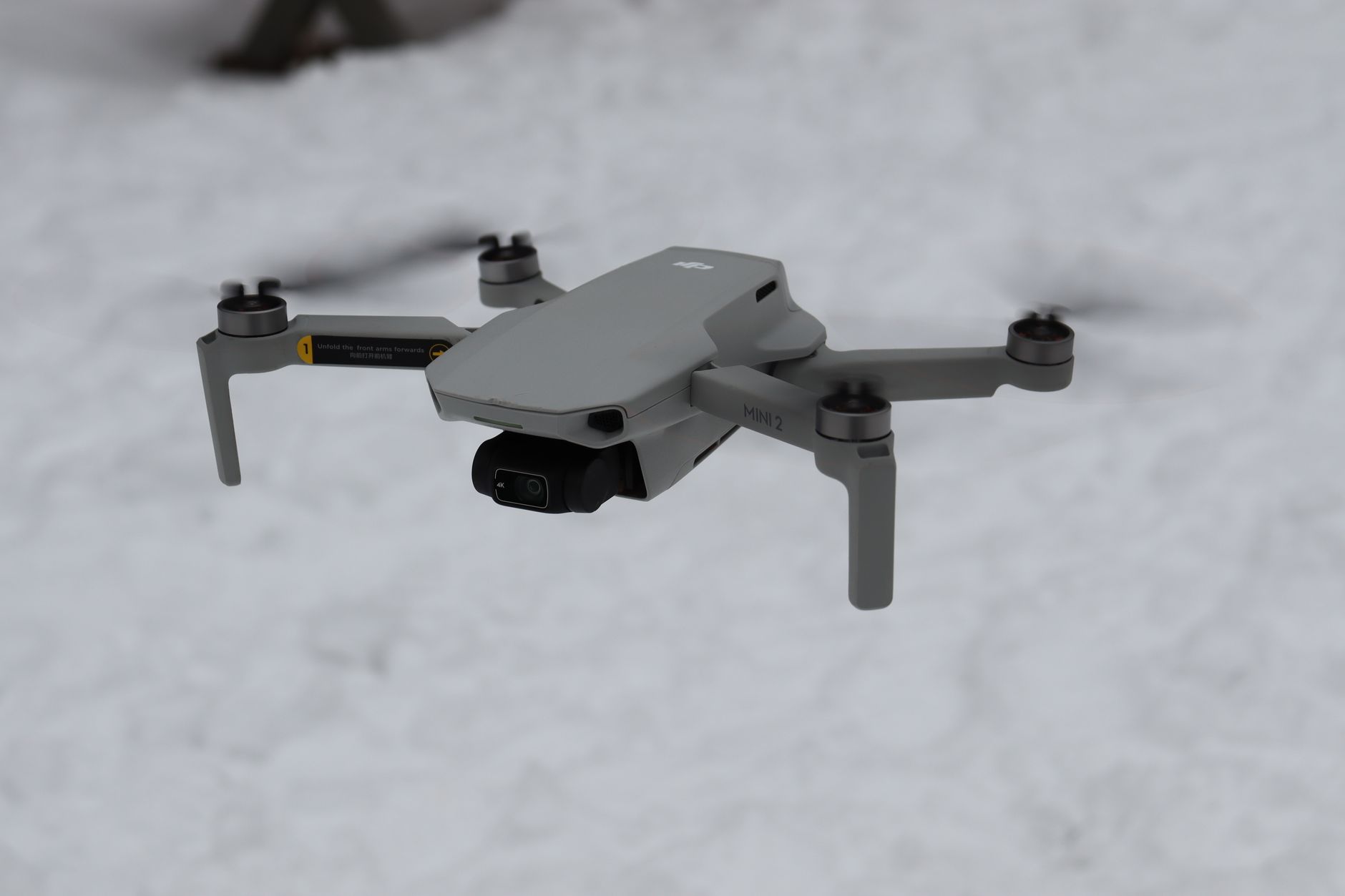a compact unmanned aerial vehicle on a pre-flight staging area, surrounded by antenna hardware and ruggedized electronics modules in an outdoor military testing environment