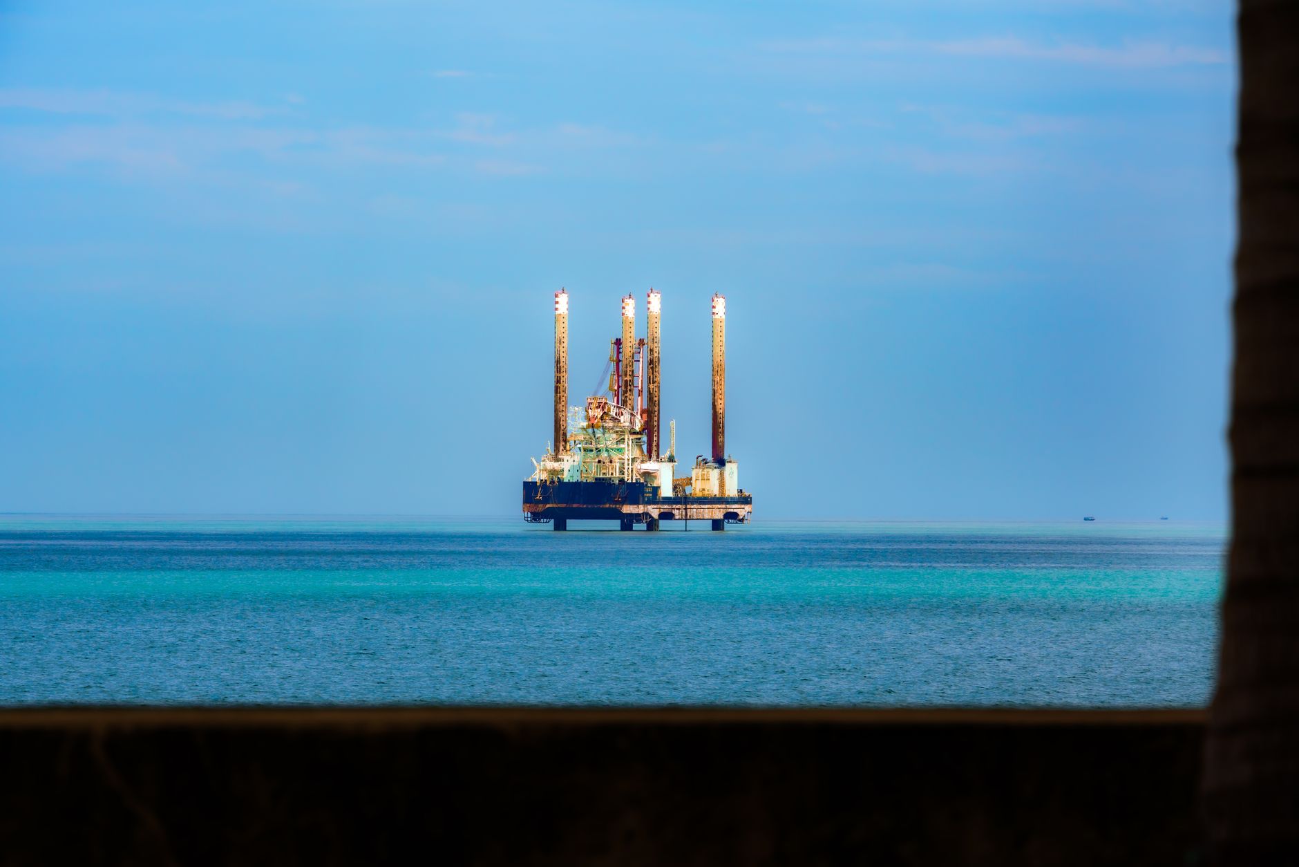close-up of industrial drilling equipment on an oil rig deck, with pipe racks and hydraulic machinery under overcast sky