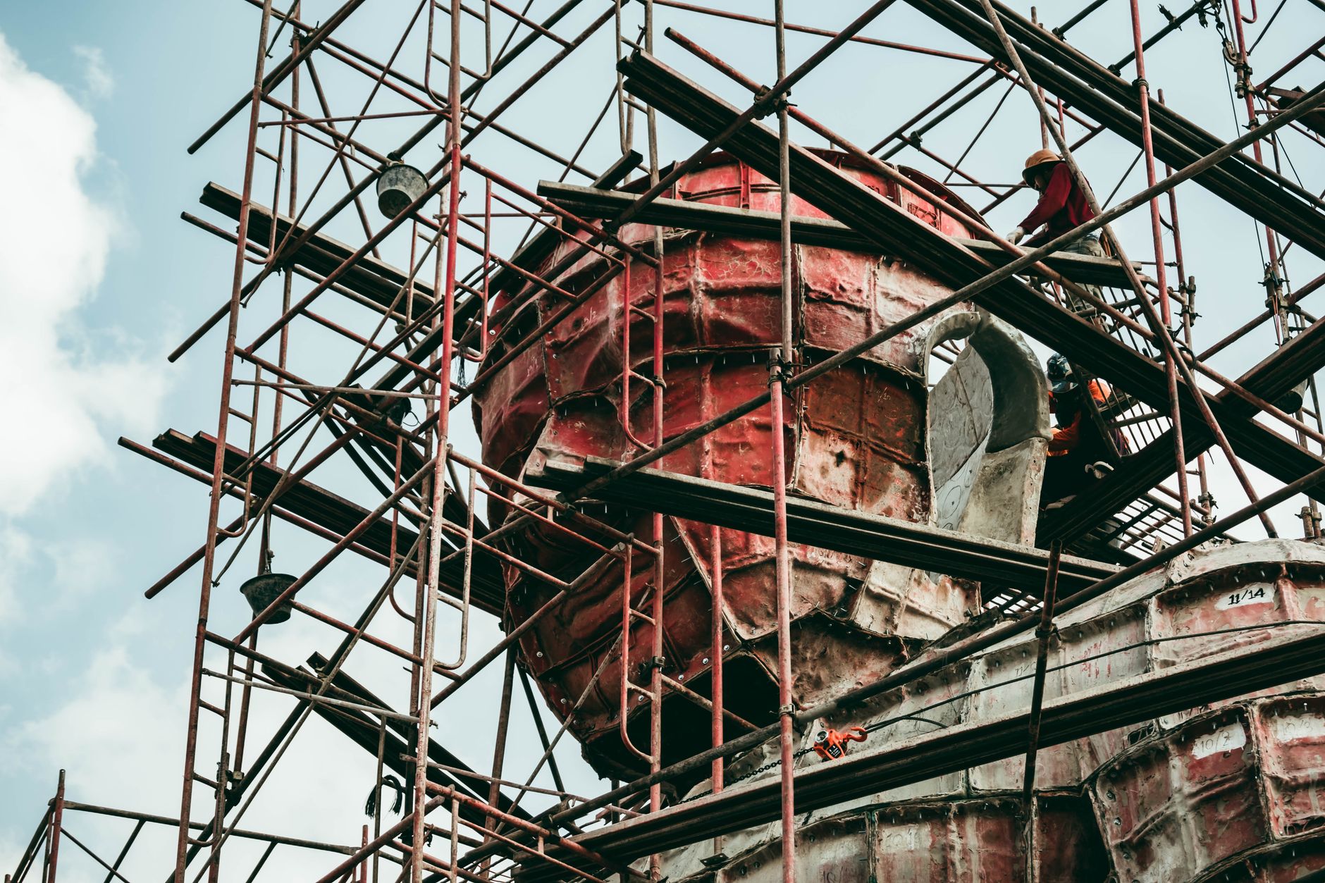 construction scaffolding surrounding a partially built nuclear reactor containment dome at an industrial construction site