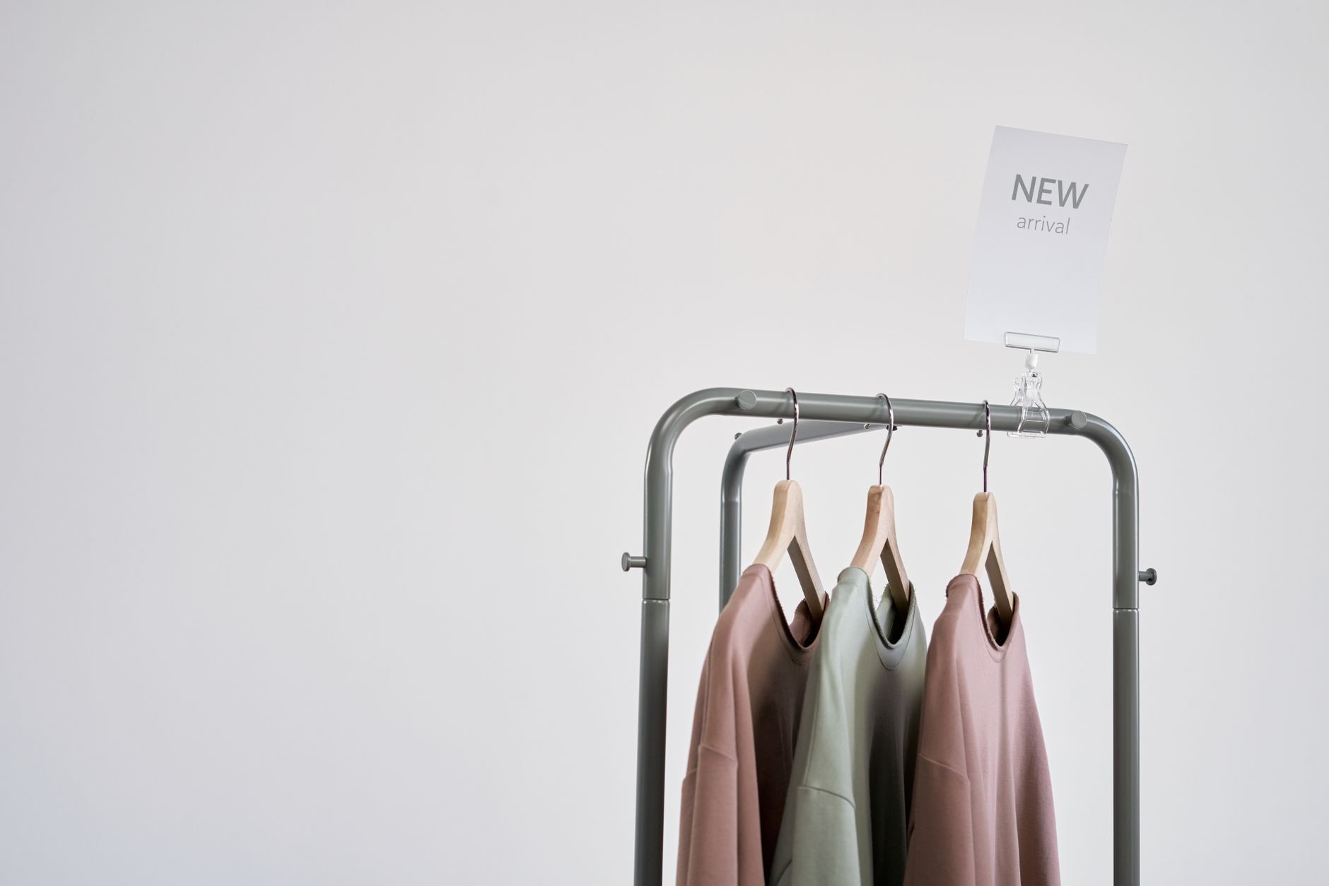 a curated high-end fashion retail display inside a minimalist boutique, garments arranged on racks under warm spotlighting with a tablet interface visible on a side table