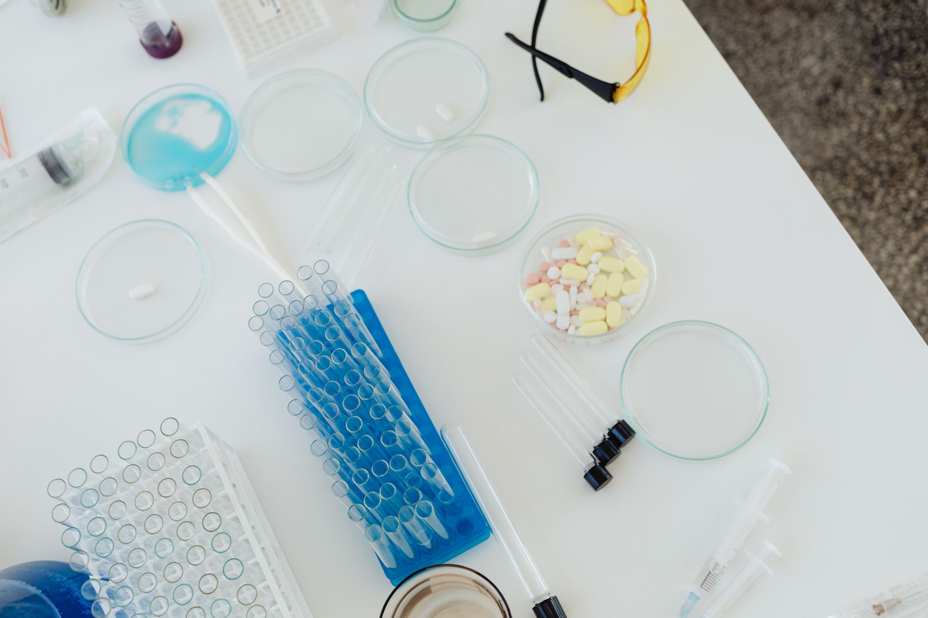 a research laboratory bench with water quality testing equipment, petri dishes, and environmental sample vials arranged under bright overhead lighting