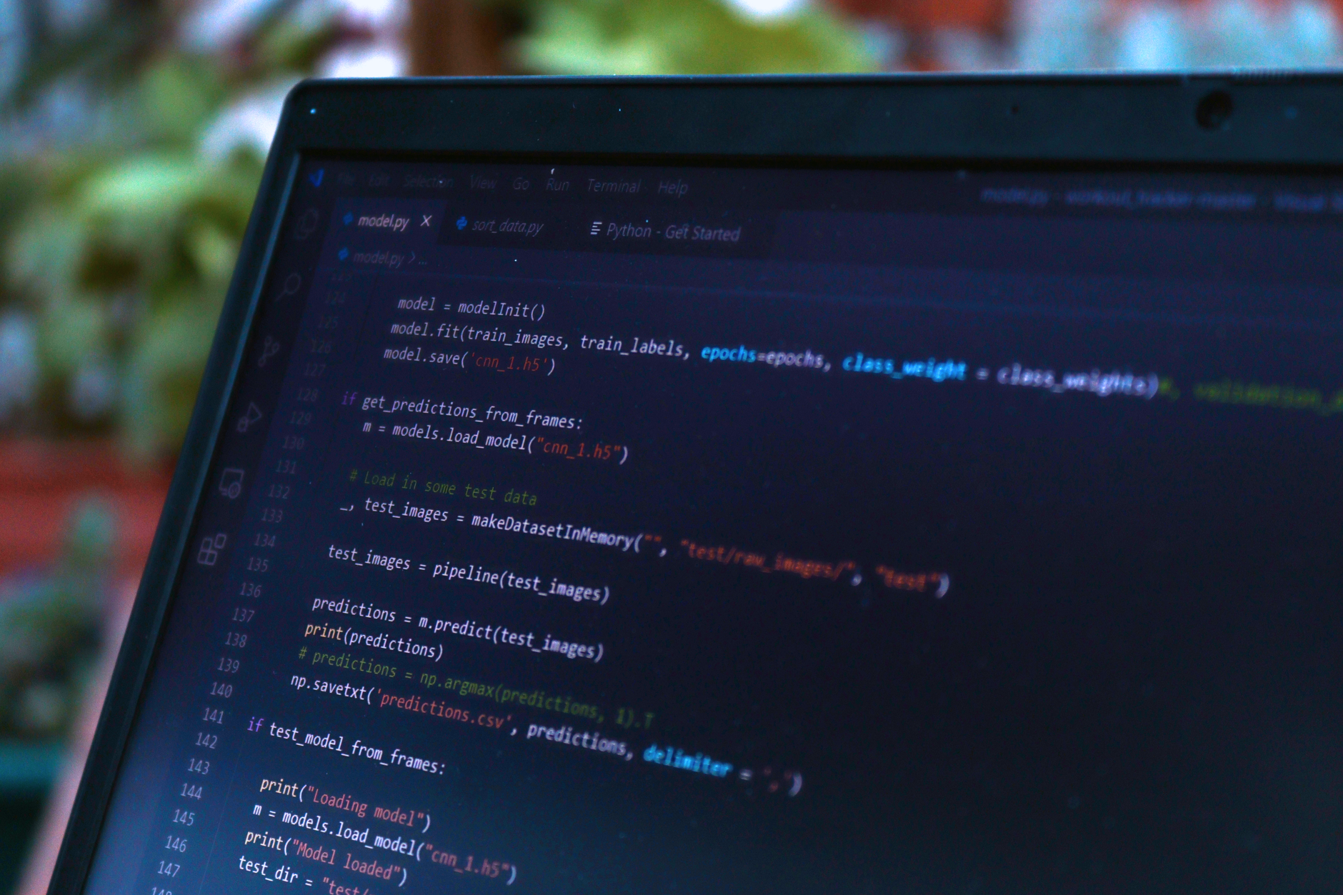 close-up of a laptop screen showing lines of automated test code running against an AI model output log in a dimly lit workspace