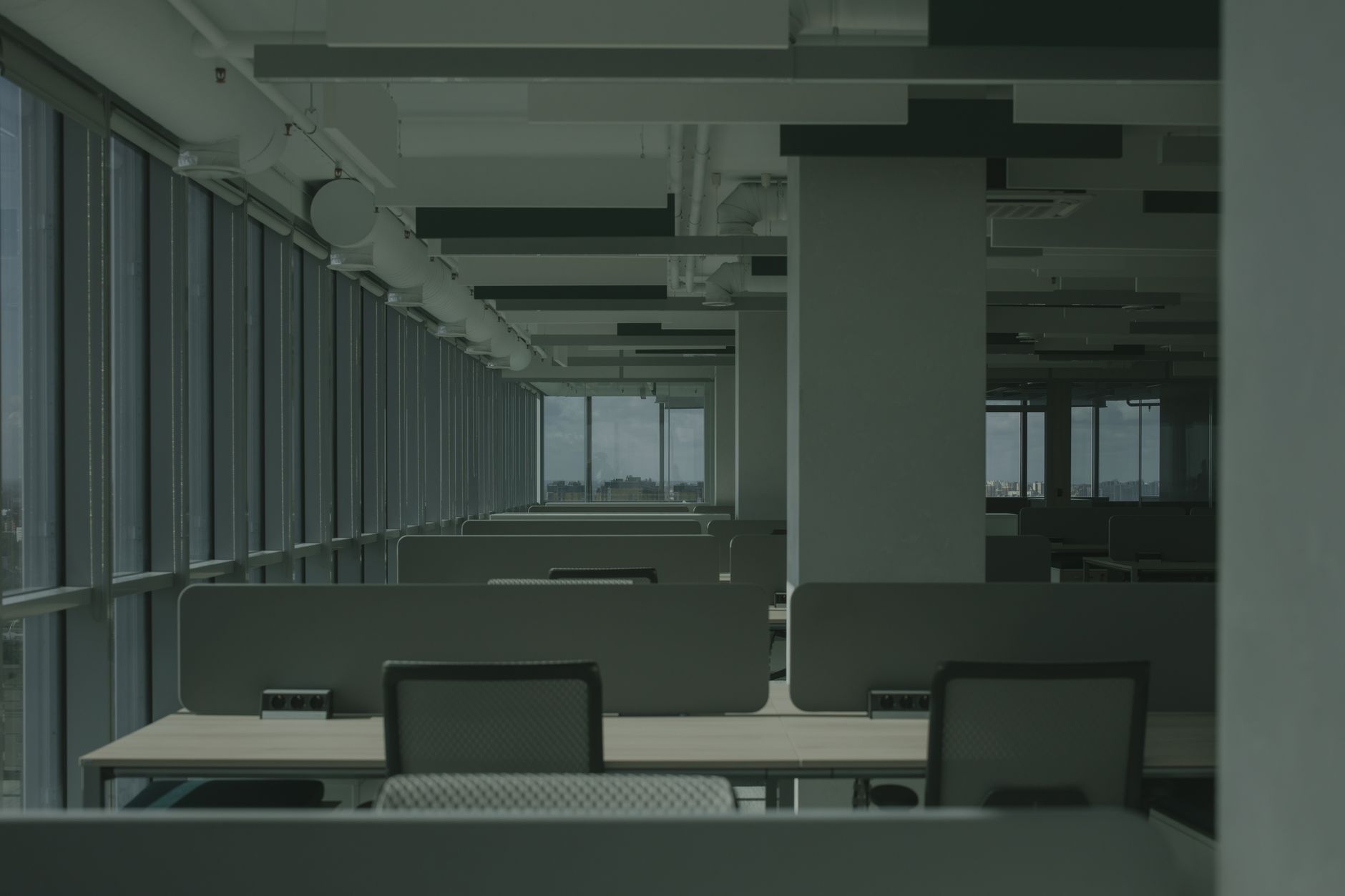 a wide-angle view of a modern corporate research lab with multiple workstations displaying data dashboards and open browser windows, empty coffee cups on desks, fluorescent lighting overhead