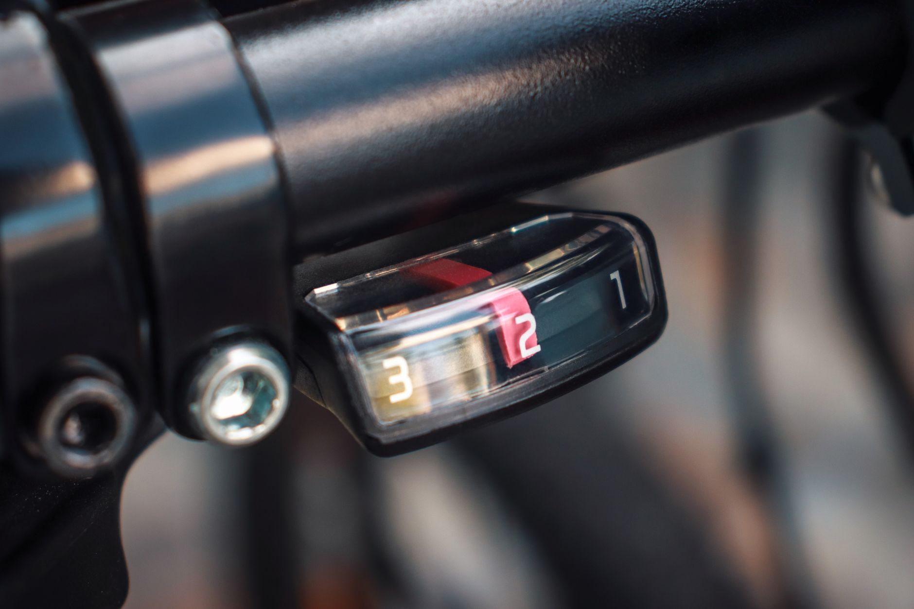 Close-up of a 36-volt battery pack mounted to the down tube of an e-bike frame, charging port visible alongside a minimalist LCD handlebar display