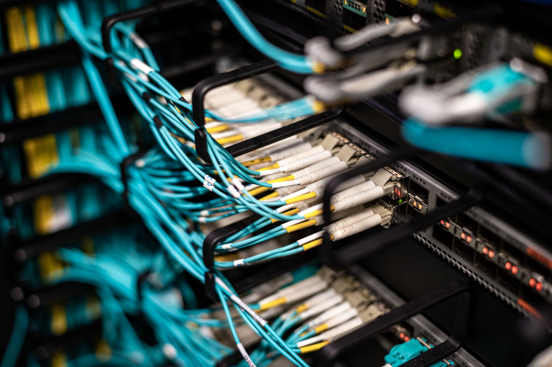 rows of neatly organized server hardware inside a mid-size cloud data center, cables color-coded and routed through metal trays above the aisles