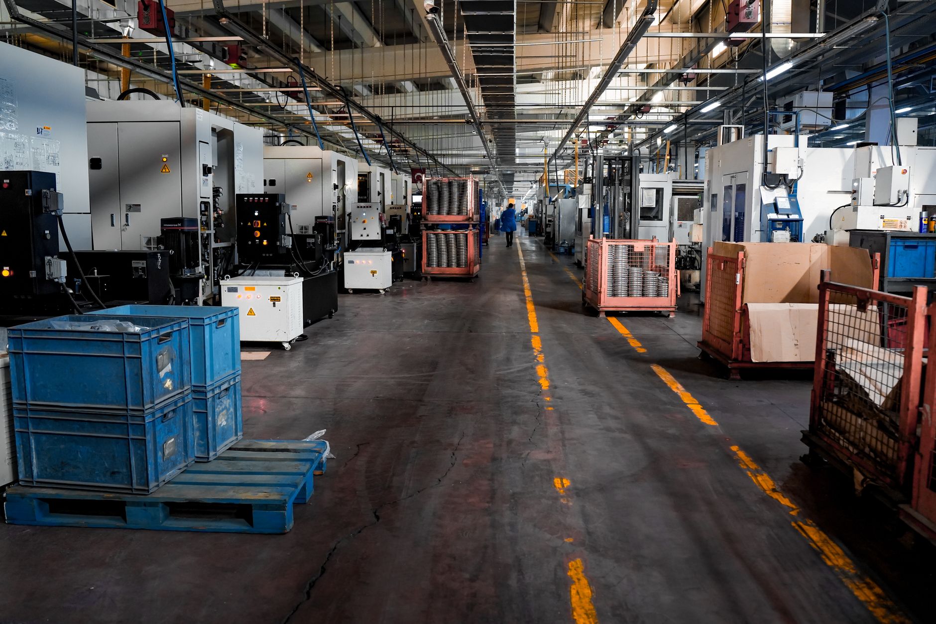 a clean aerospace manufacturing floor with flat-panel satellite components arranged on assembly fixtures under bright industrial lighting