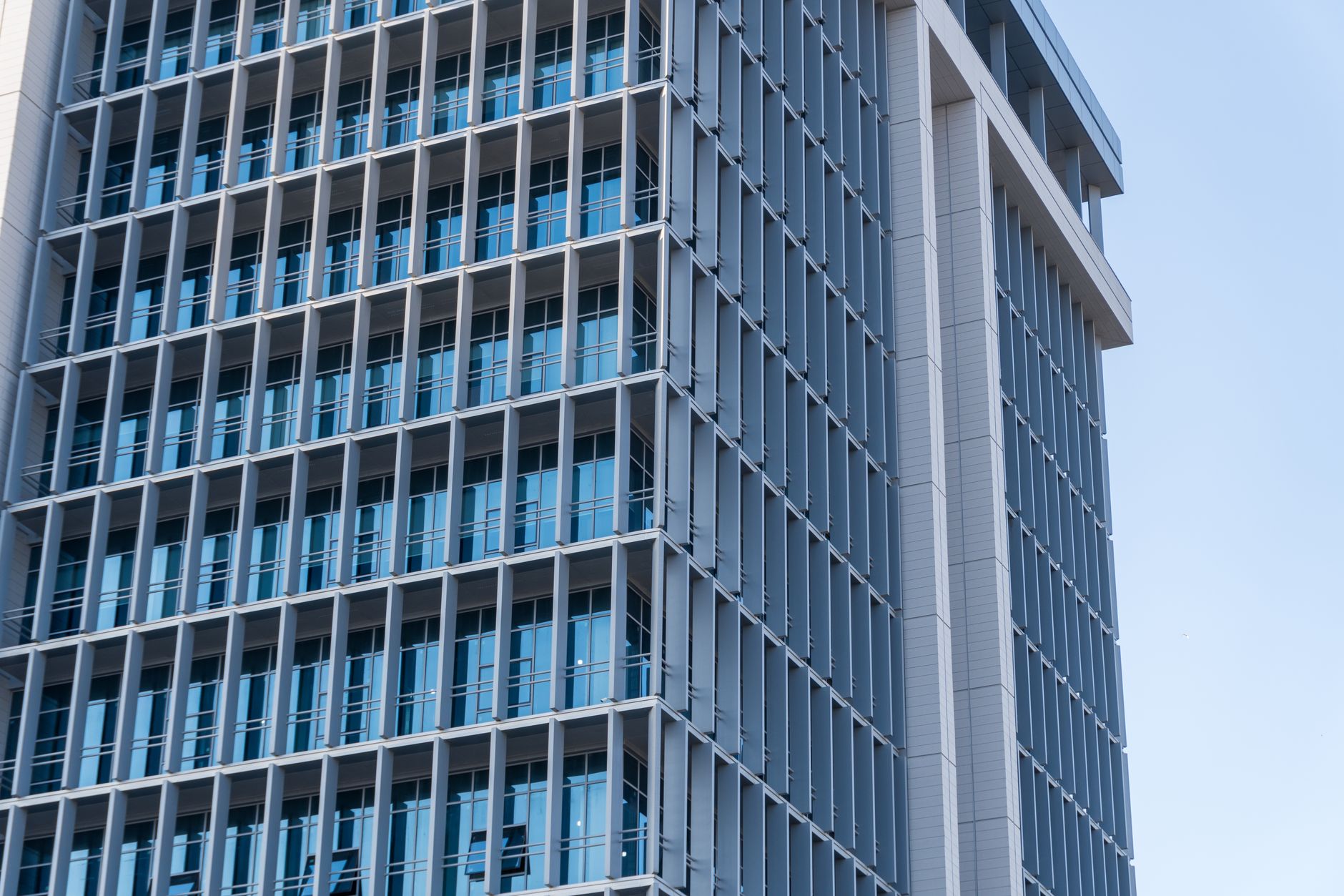 the exterior of a nondescript financial services office building with a glass facade reflecting a city skyline at midday