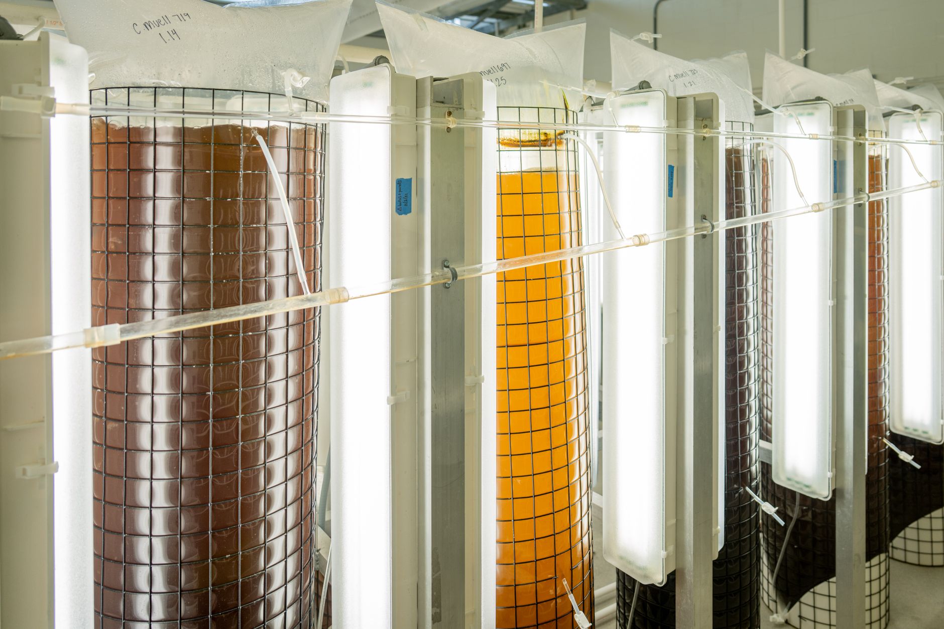rows of unmanned aerial vehicle frames in various stages of assembly inside a large industrial production floor, lit by overhead fluorescent lighting