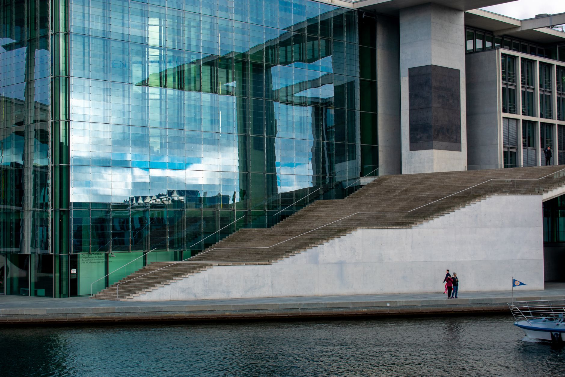 exterior of a federal courthouse in late afternoon light, concrete steps and glass entry doors visible