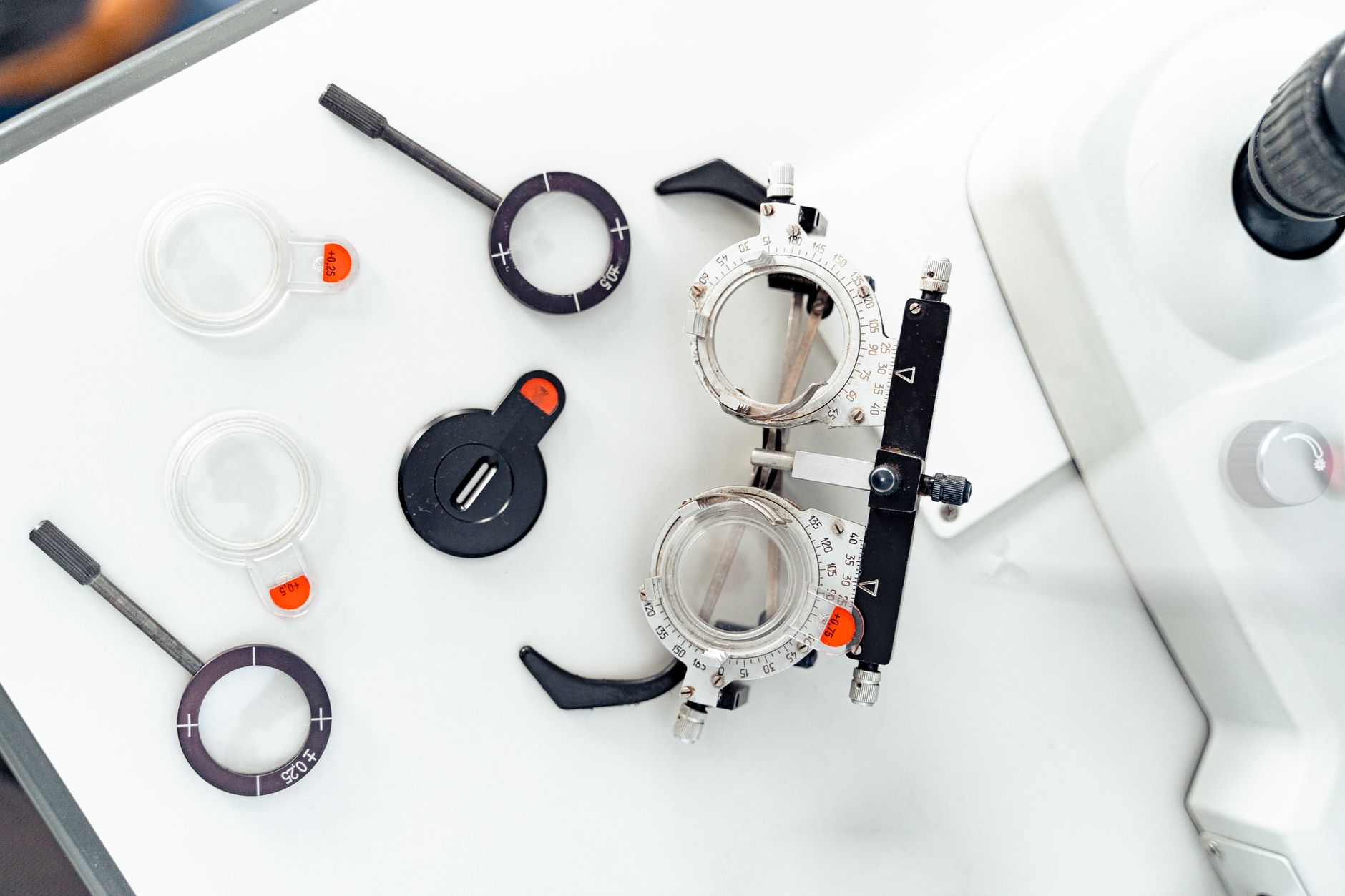 close-up of a modern in-ear hearing aid device resting on a white clinical testing surface next to precision measurement instruments